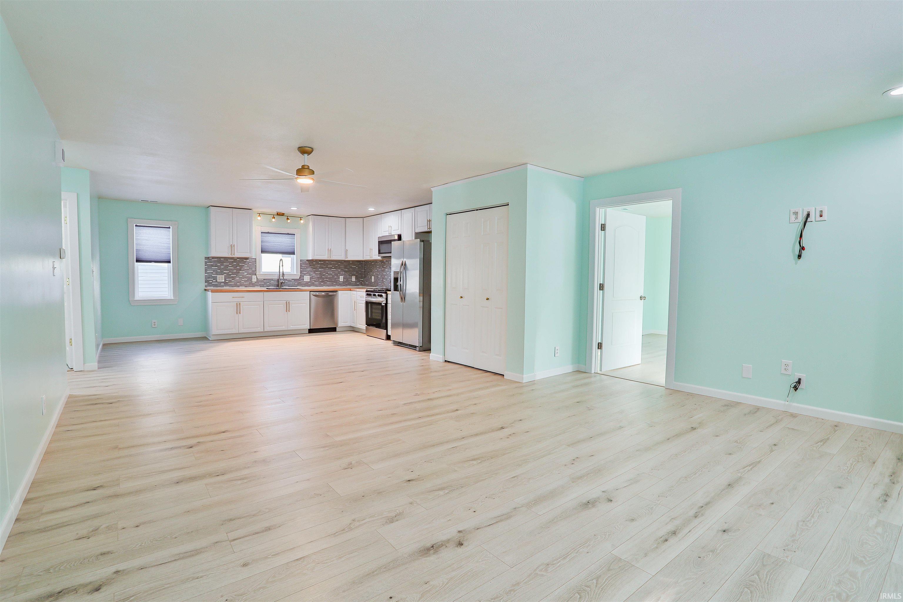 Unfurnished living room with ceiling fan and light wood-style floors