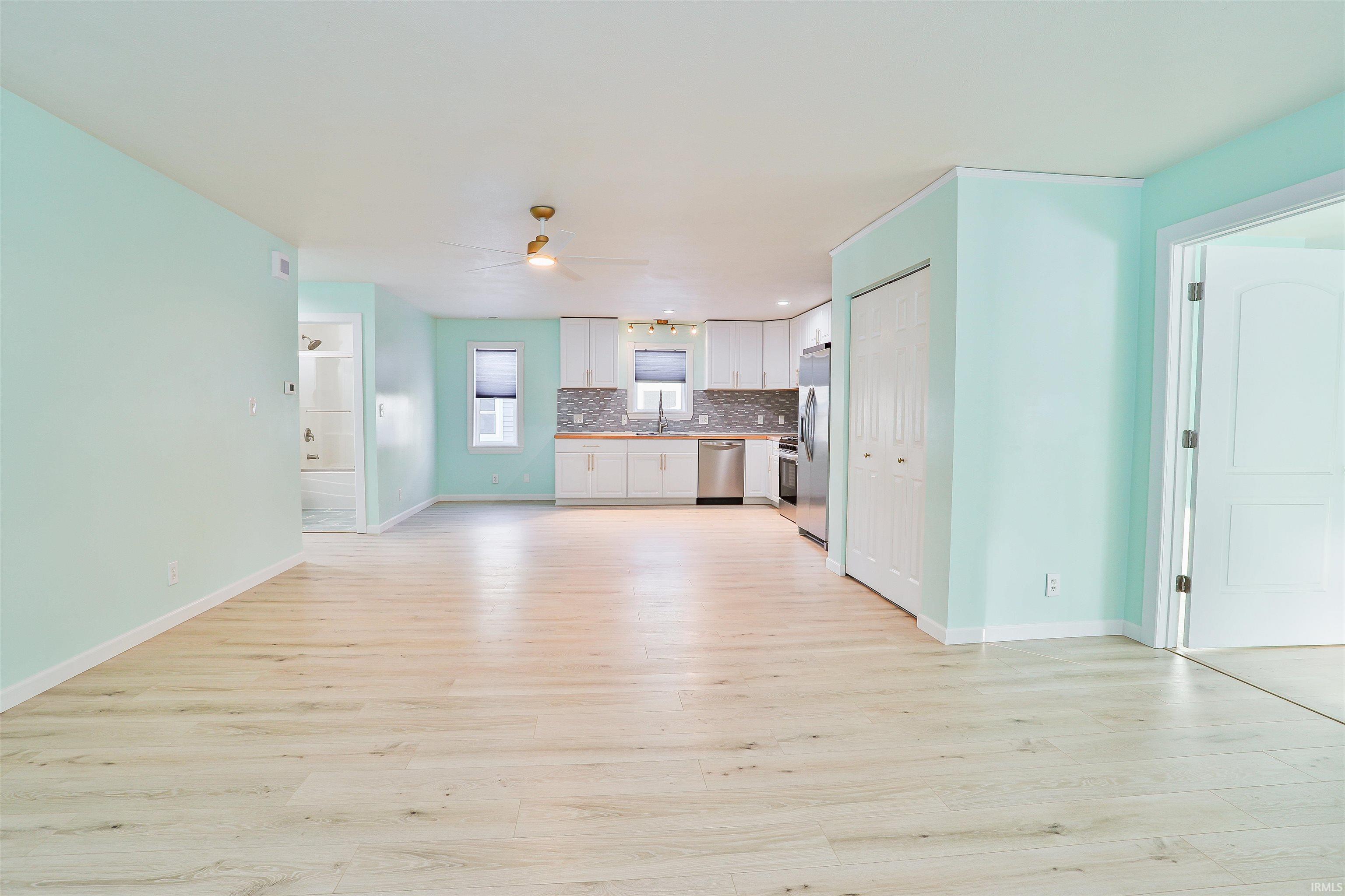 Unfurnished living room featuring light wood-type flooring and a ceiling fan