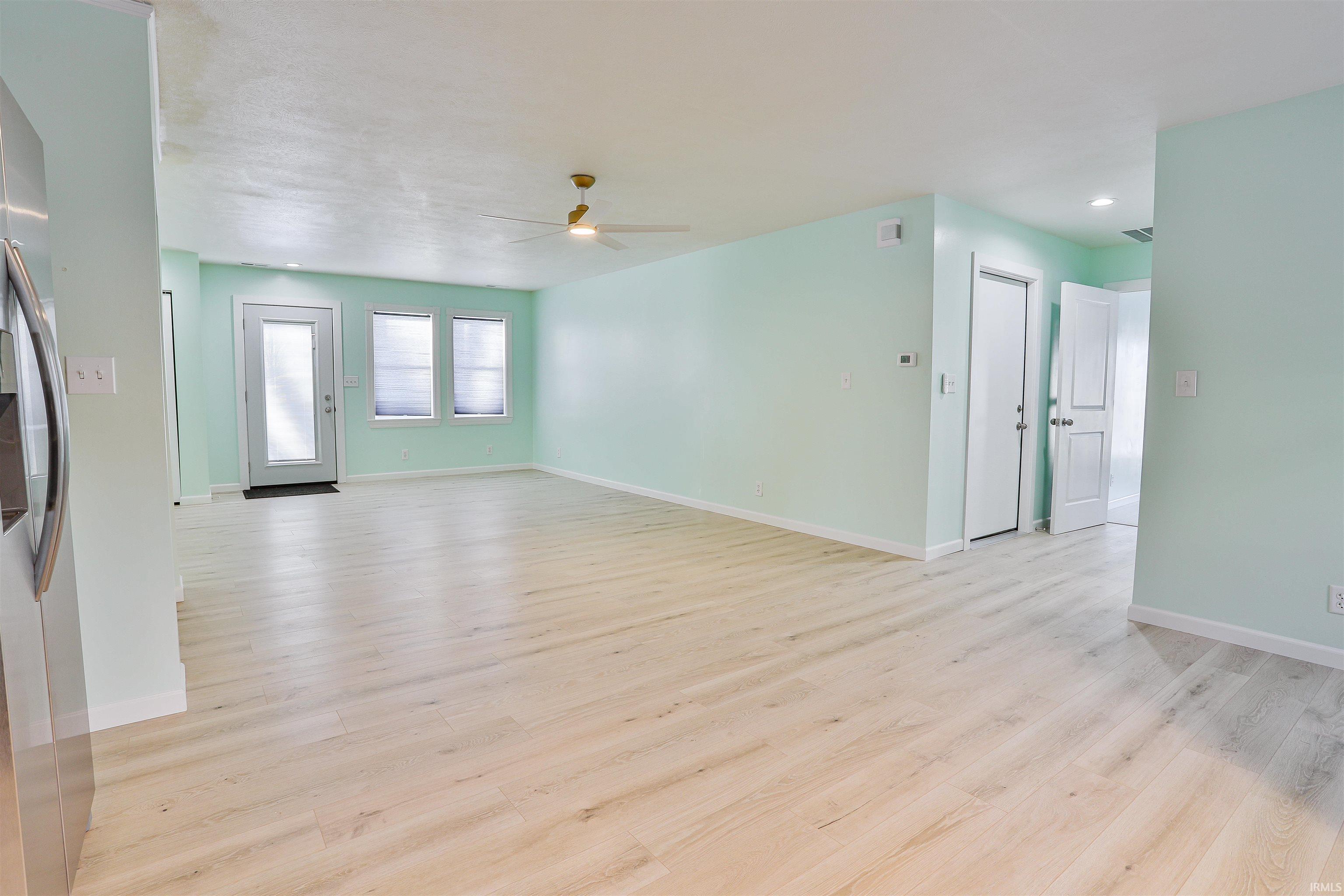 Unfurnished living room featuring light wood-type flooring and ceiling fan