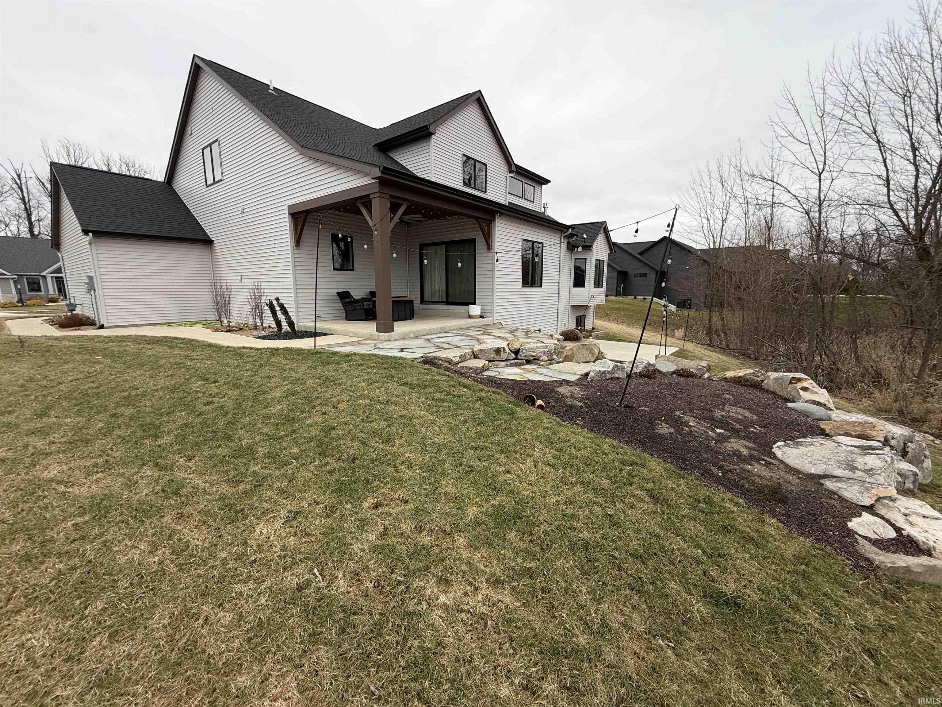 Back of property with a patio, a yard, and a shingled roof