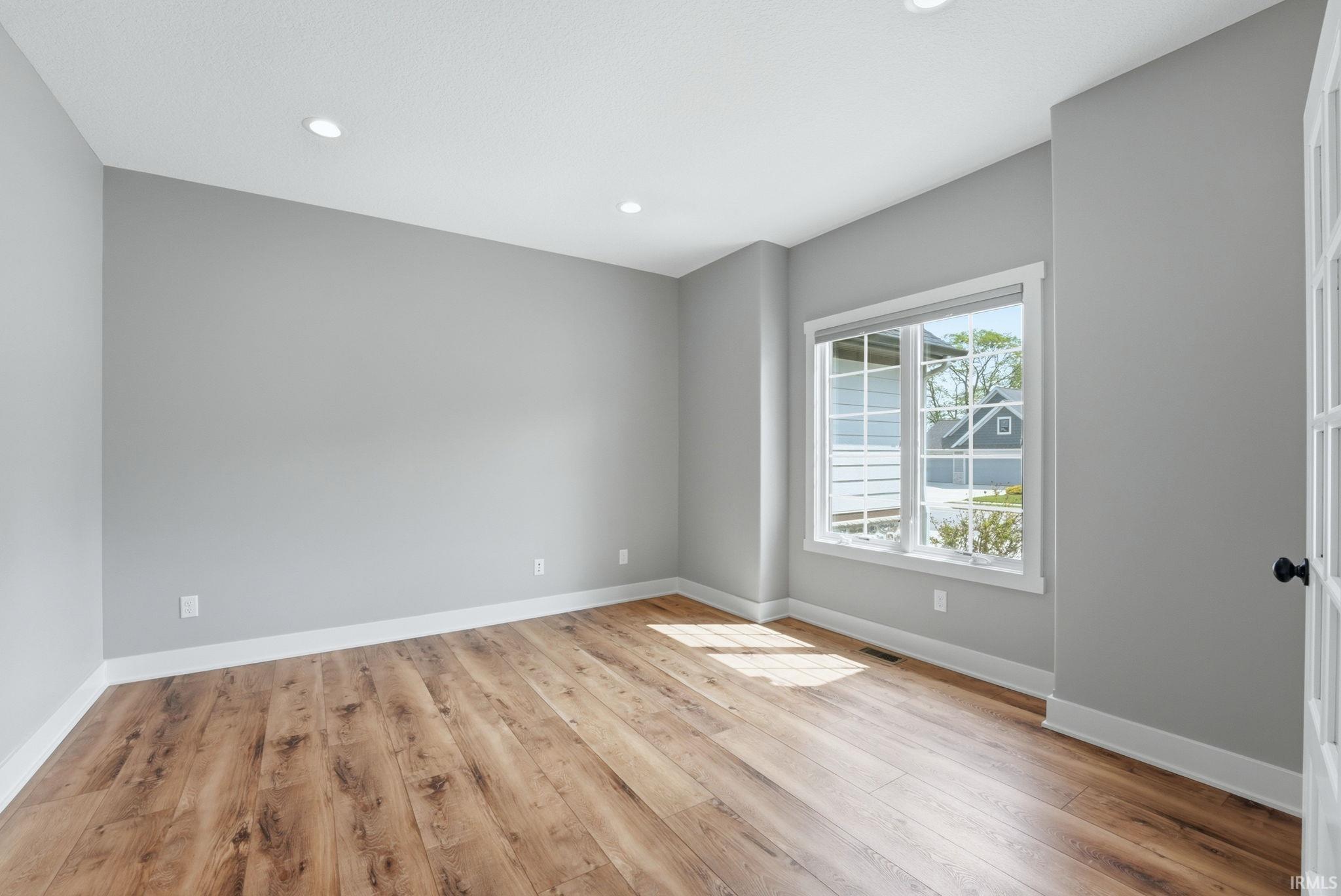 Spacious room featuring light gray walls, white trim, and recessed lighting