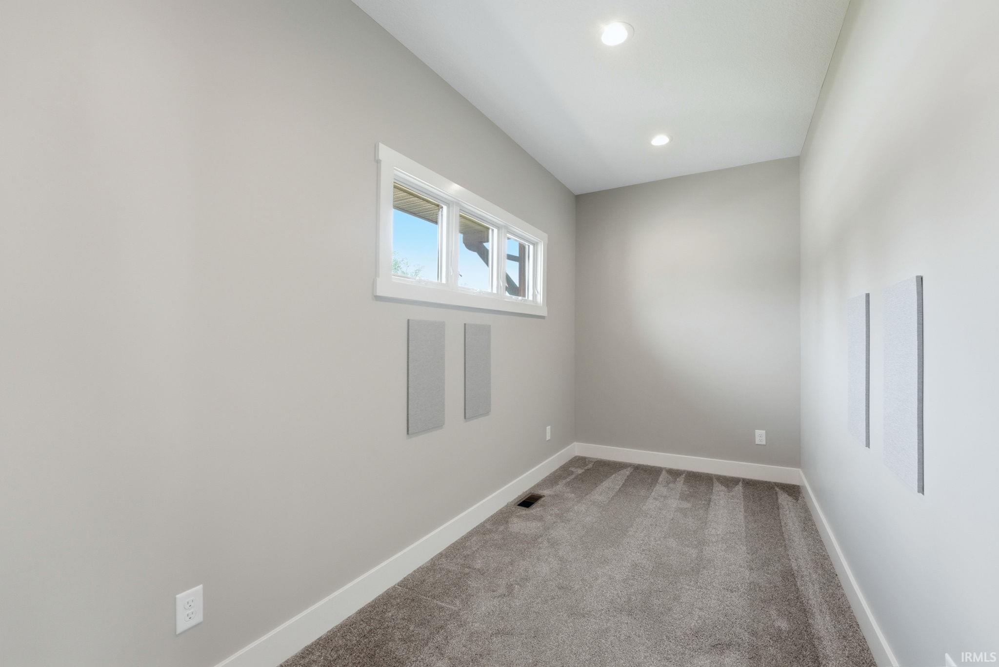 Recessed lighting illuminates this room featuring light gray walls, white trim, and gray patterned carpeting