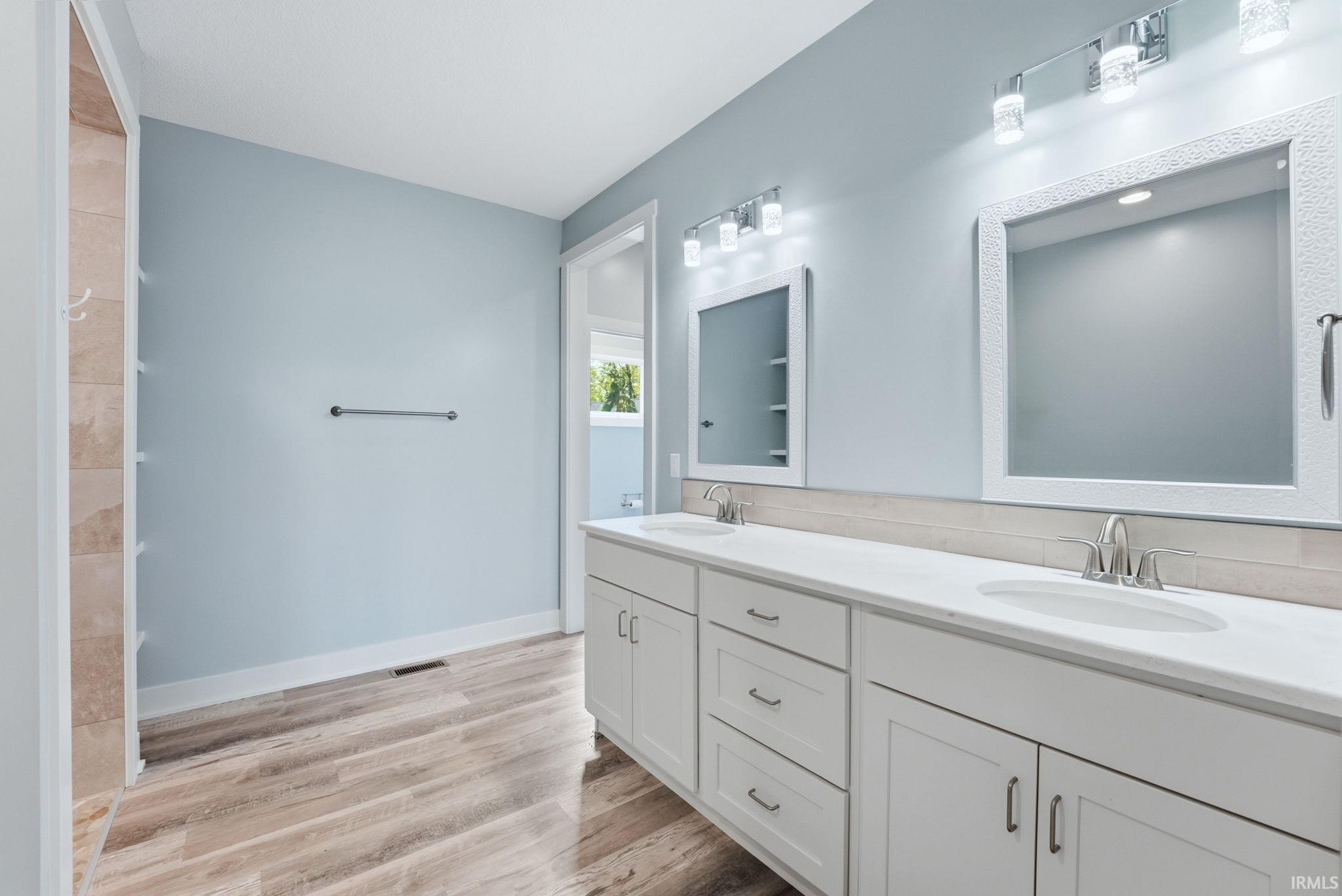 Dual vanity with white cabinetry, integrated sinks, and brushed nickel fixtures