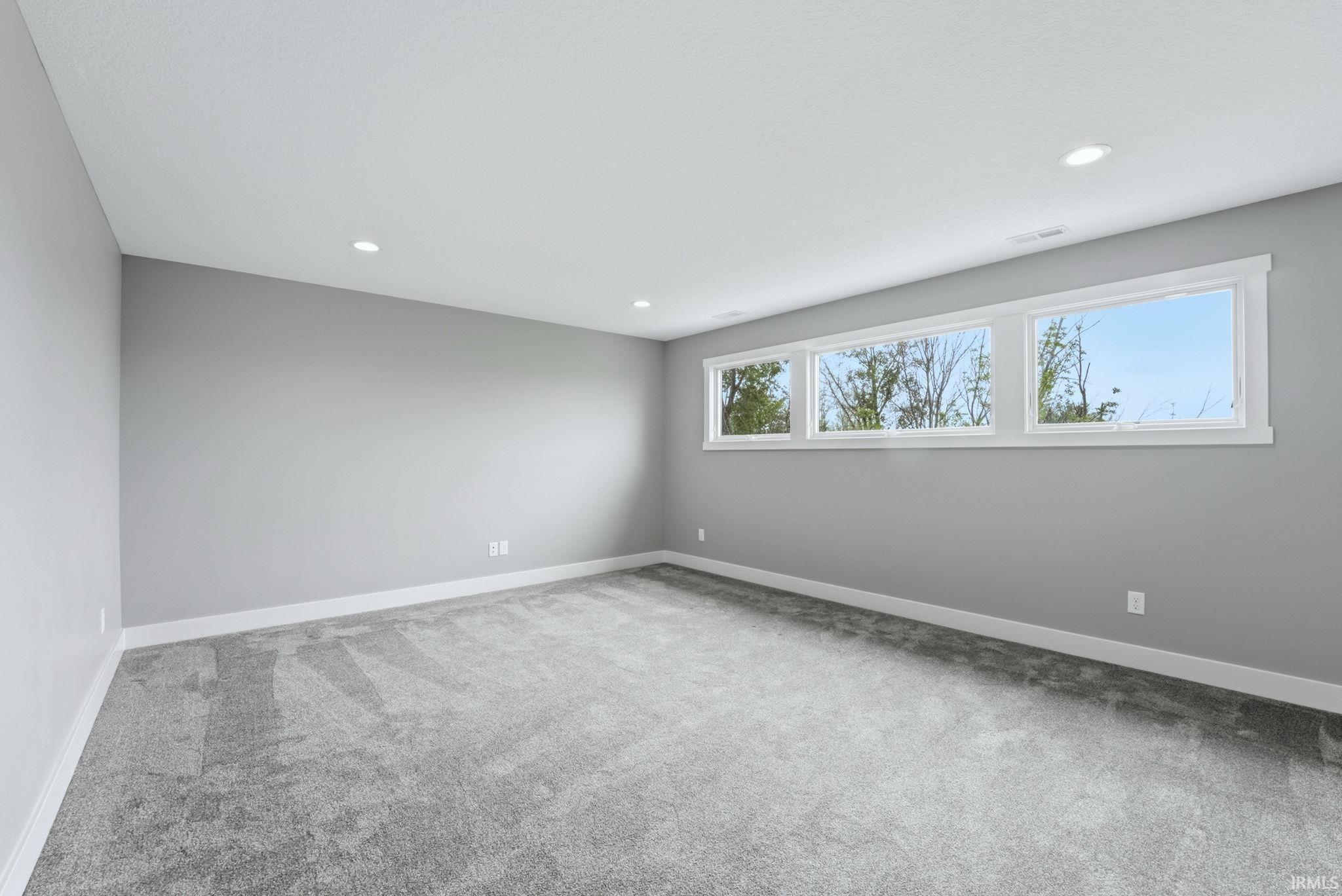 Spacious room featuring three expansive transom windows, light gray wall paint, white trim, and recessed ceiling lighting