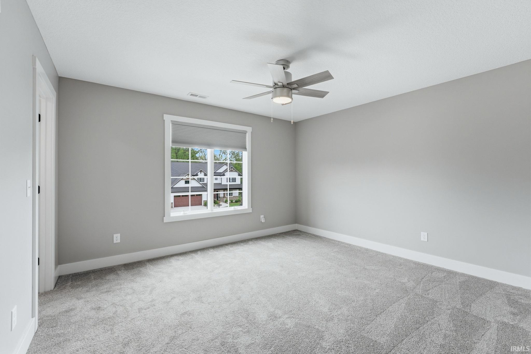 Expansive room featuring light gray carpeting and matching wall tones