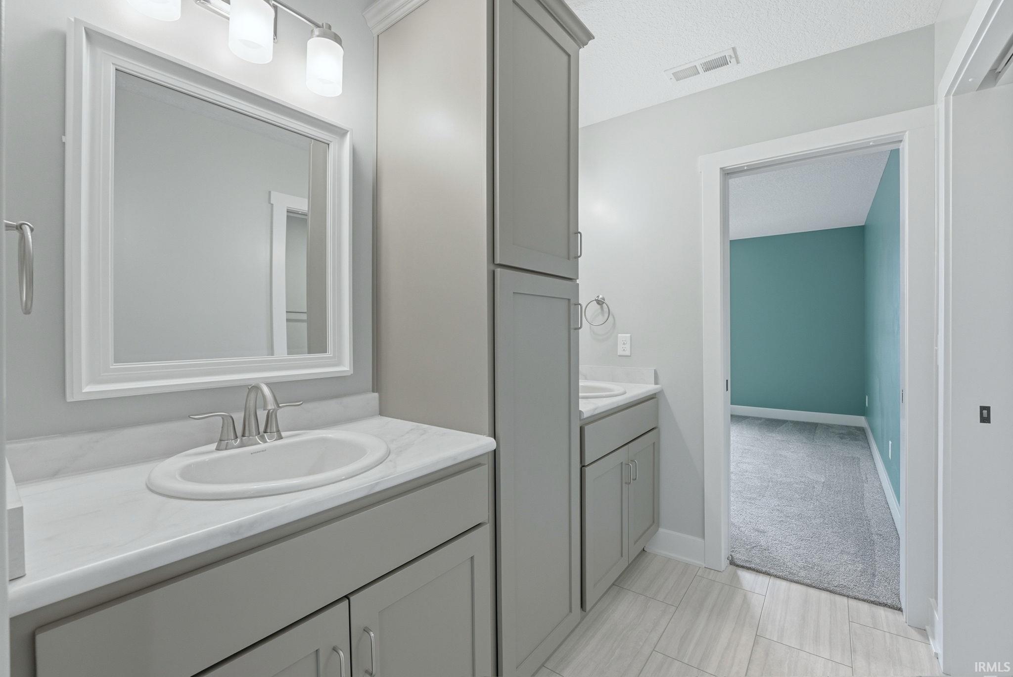 Dual vanity bathroom featuring light gray cabinetry, white countertops, and brushed nickel fixtures