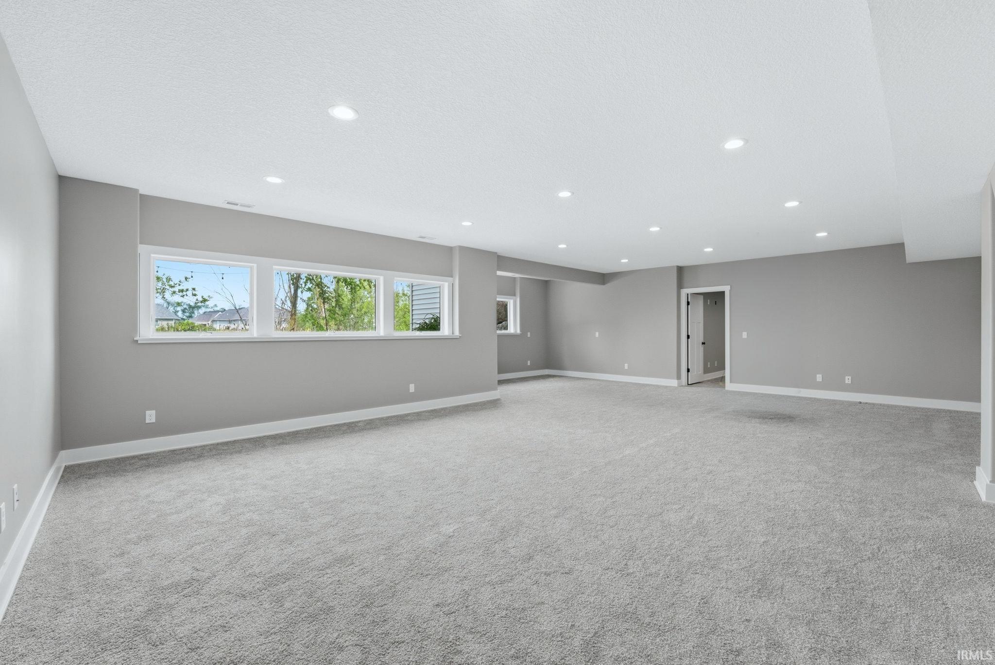 Spacious room featuring light gray walls, white trim, and light gray carpeting
