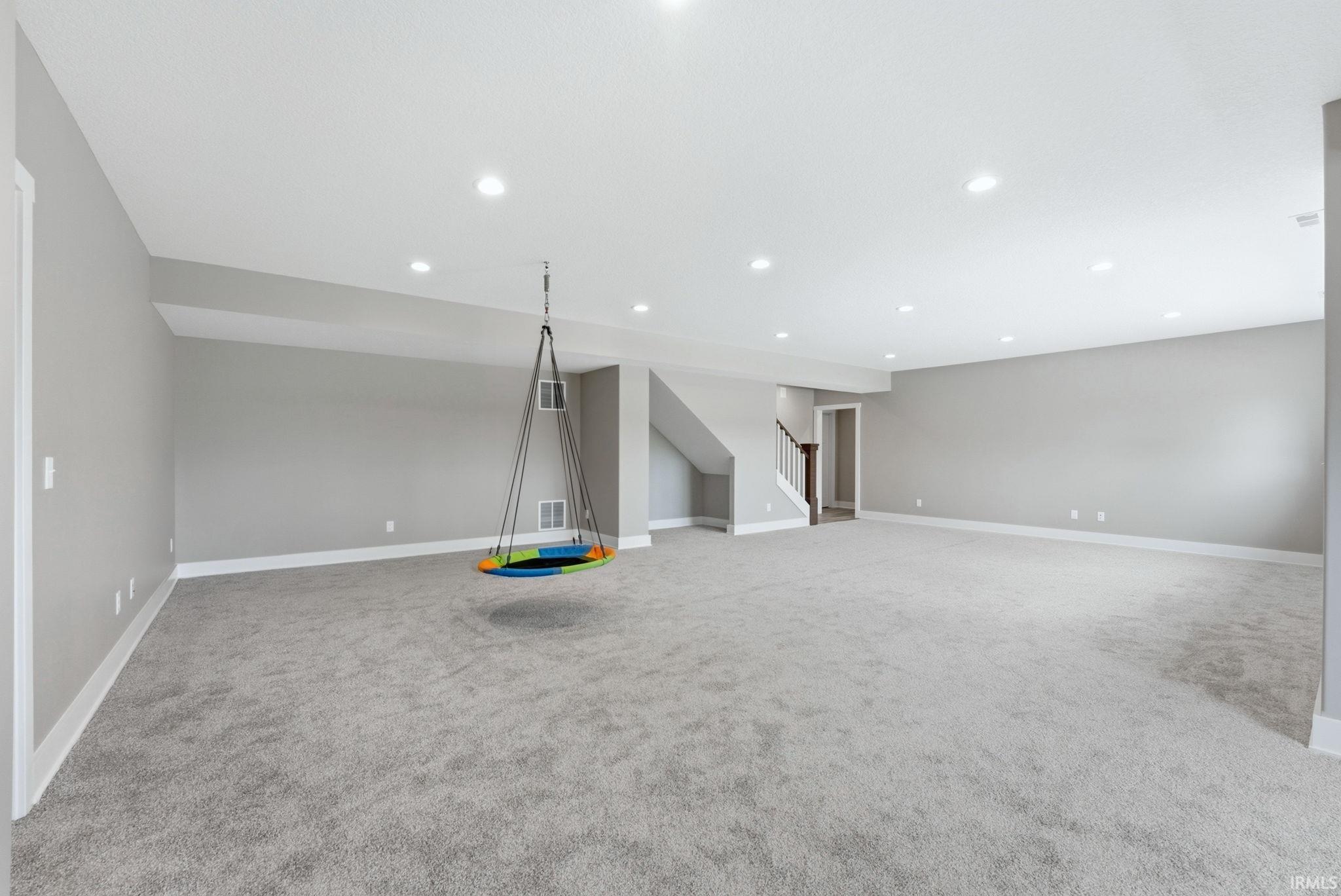 Spacious open-concept room featuring light gray carpet flooring, white baseboards, and recessed ceiling lighting