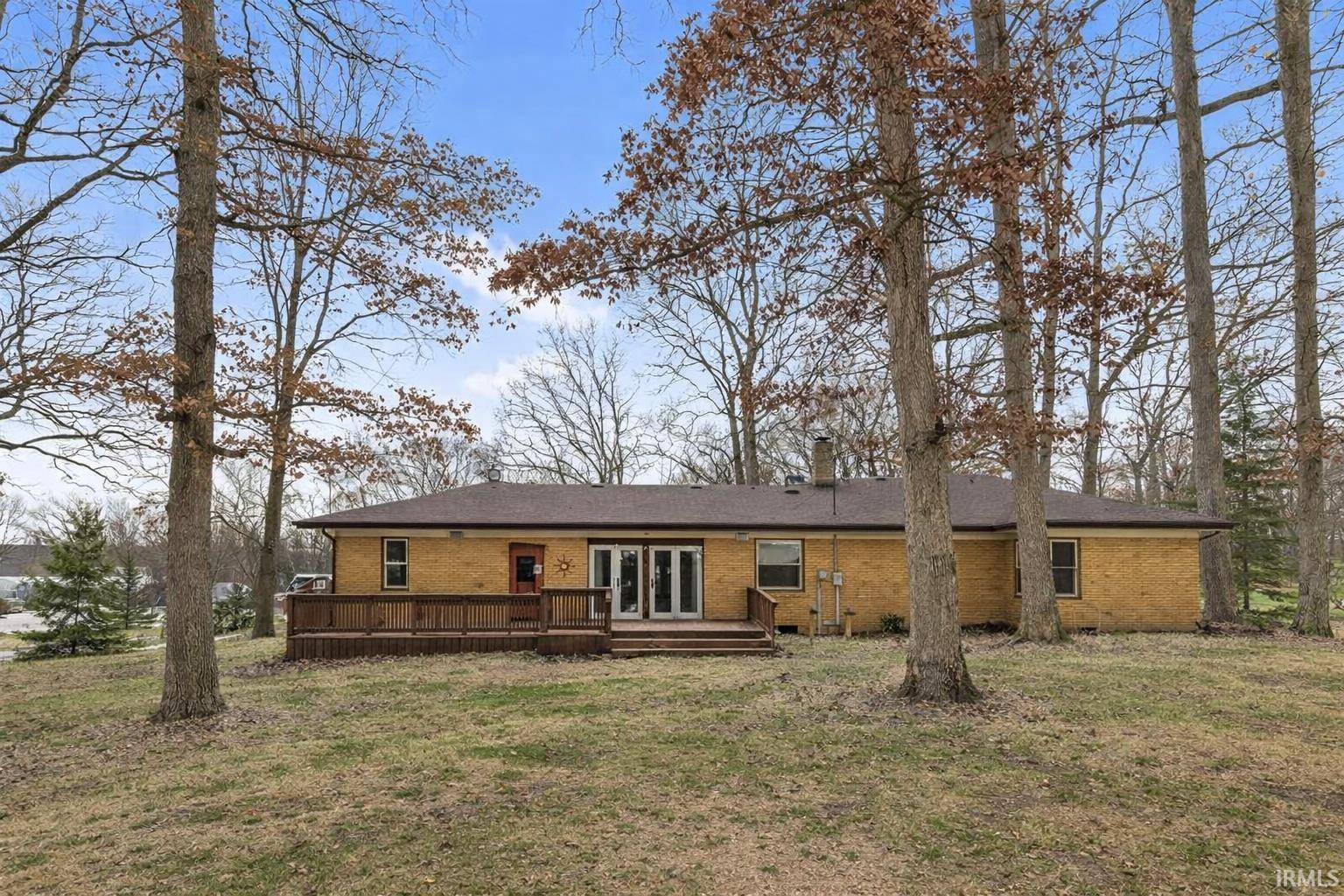 View of front of home featuring brick siding, a deck, french doors, and a front lawn