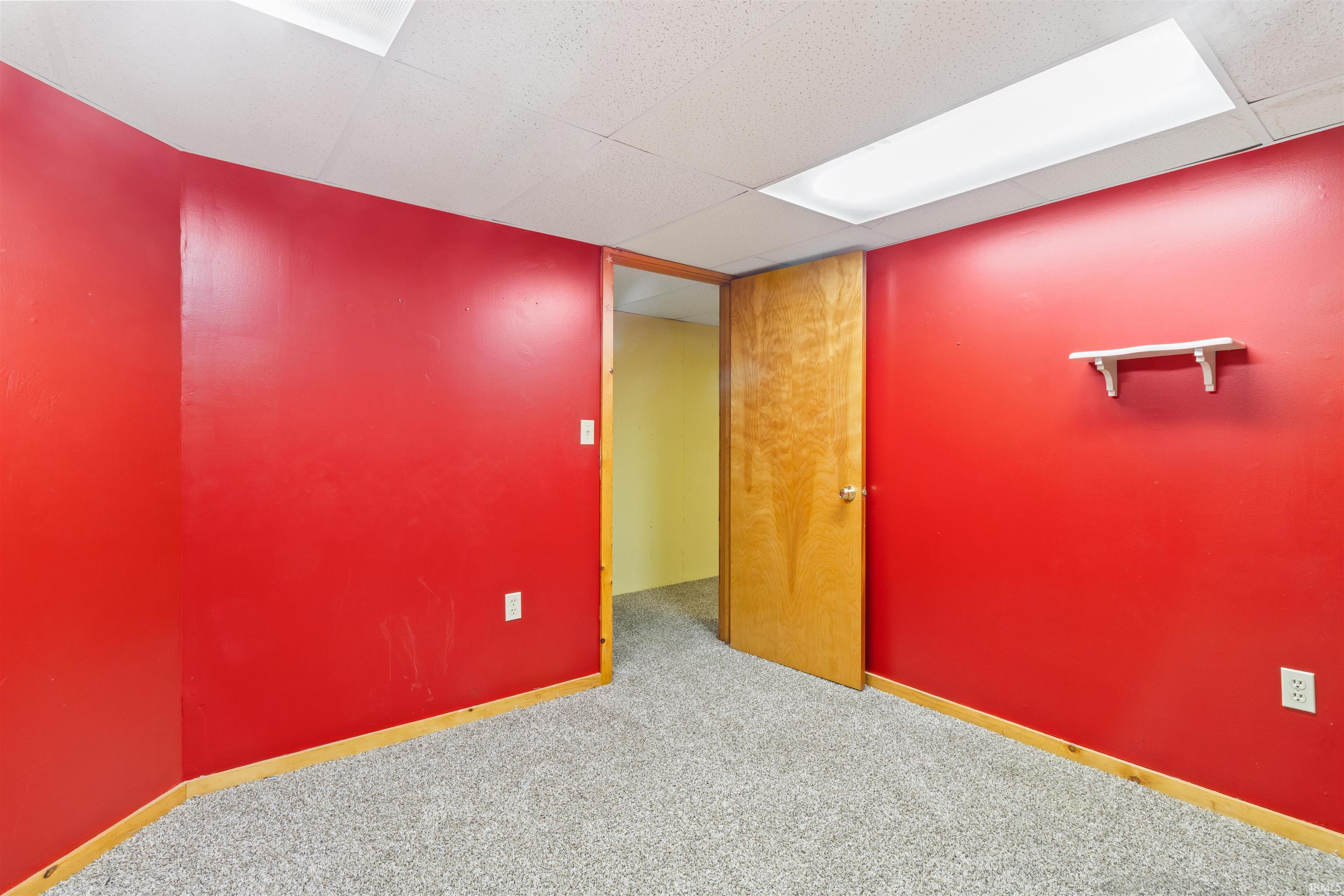 Carpeted empty room with a paneled ceiling and baseboards