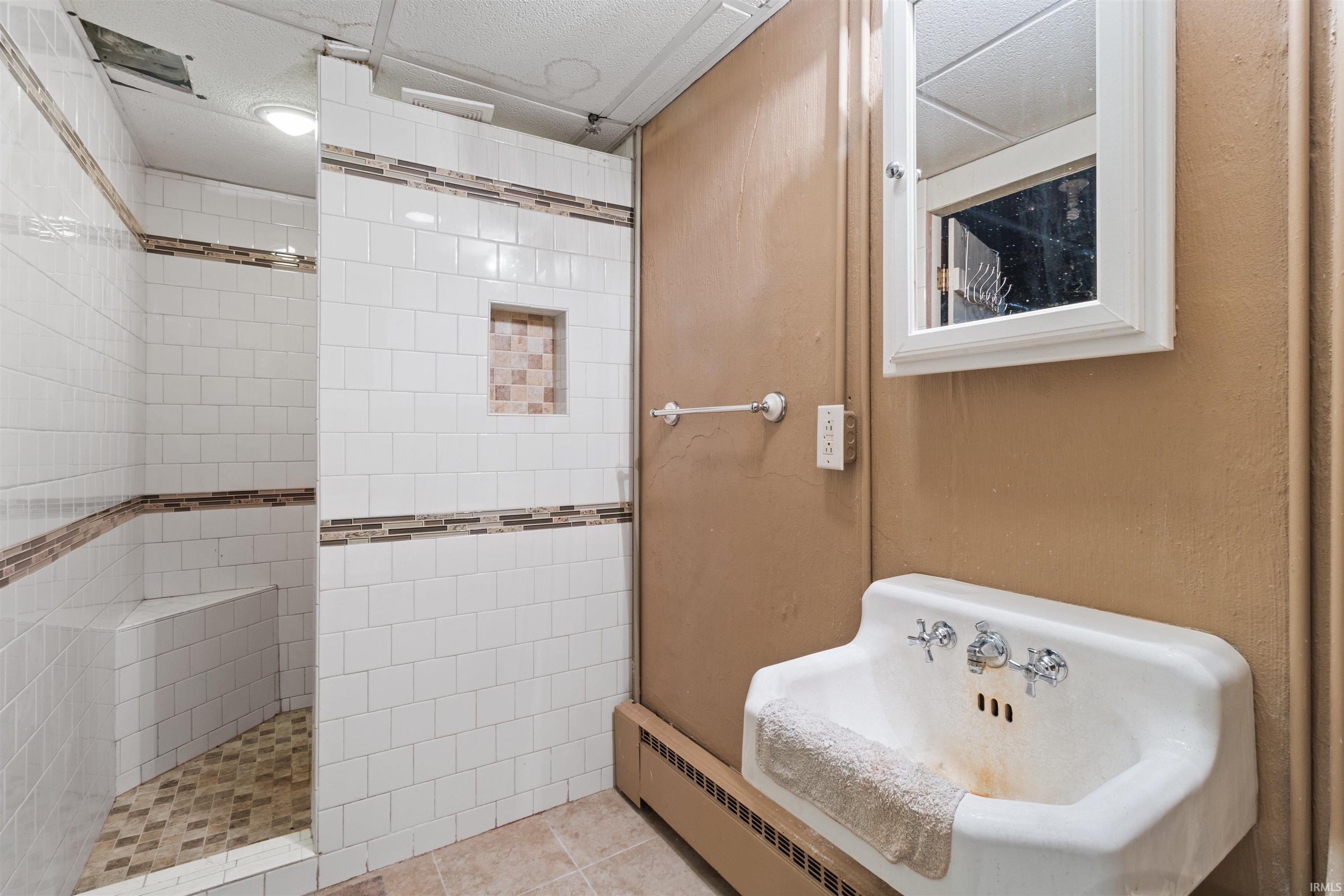 Bathroom with a baseboard heating unit and walk in shower