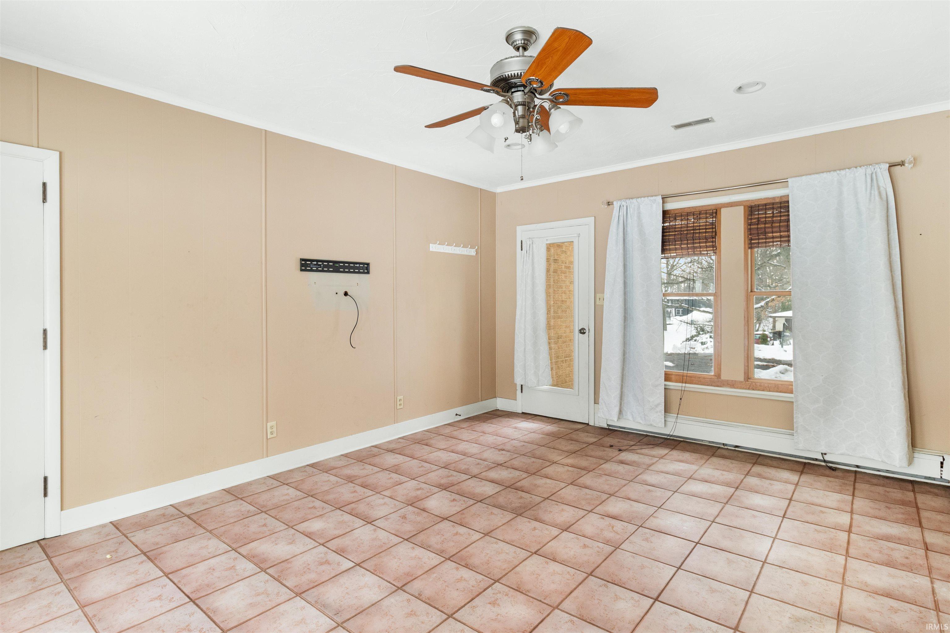 Tiled spare room featuring ornamental molding and ceiling fan
