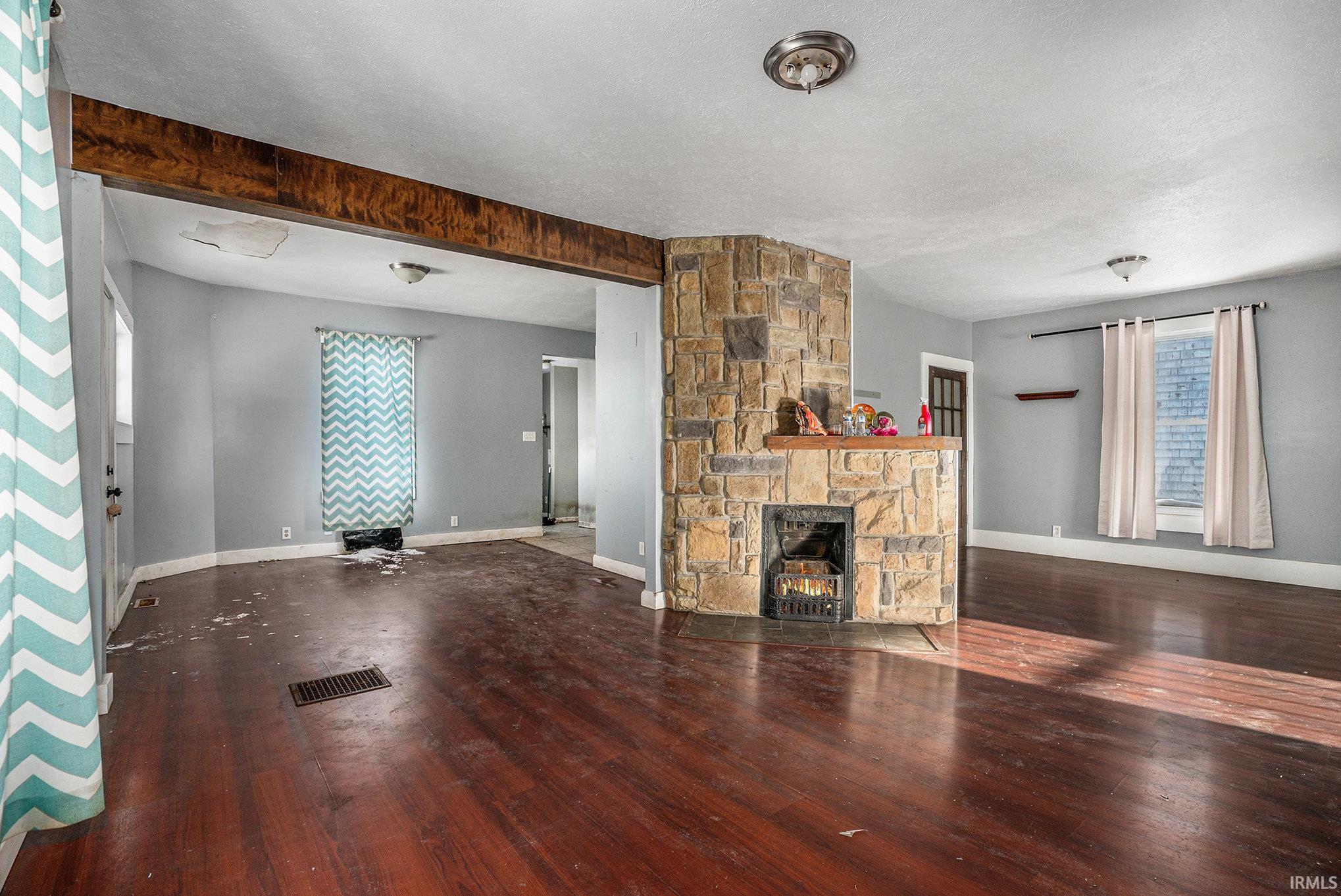 Unfurnished living room with a fireplace, a textured ceiling, and dark wood-style flooring