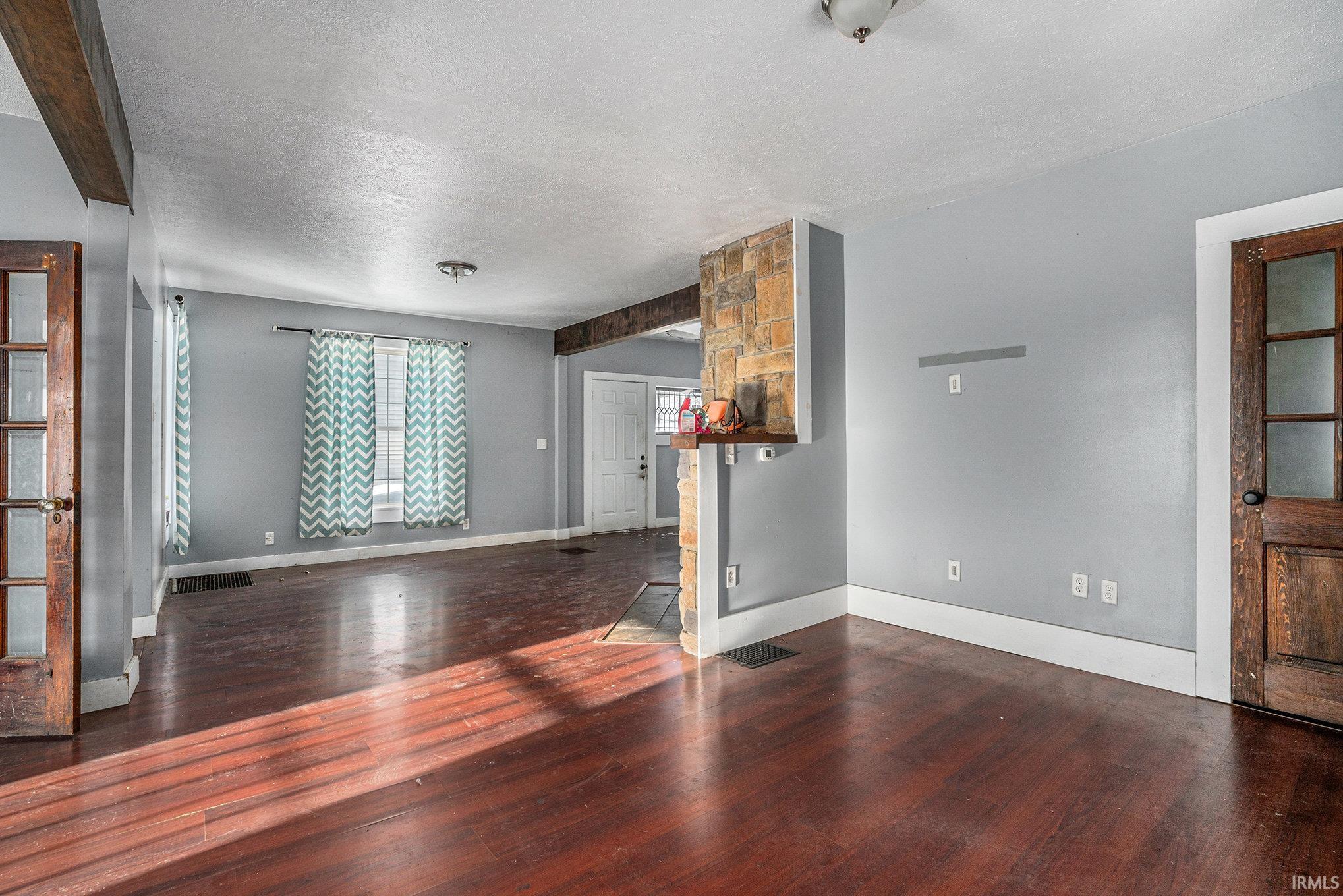 Unfurnished living room featuring dark wood finished floors and a textured ceiling