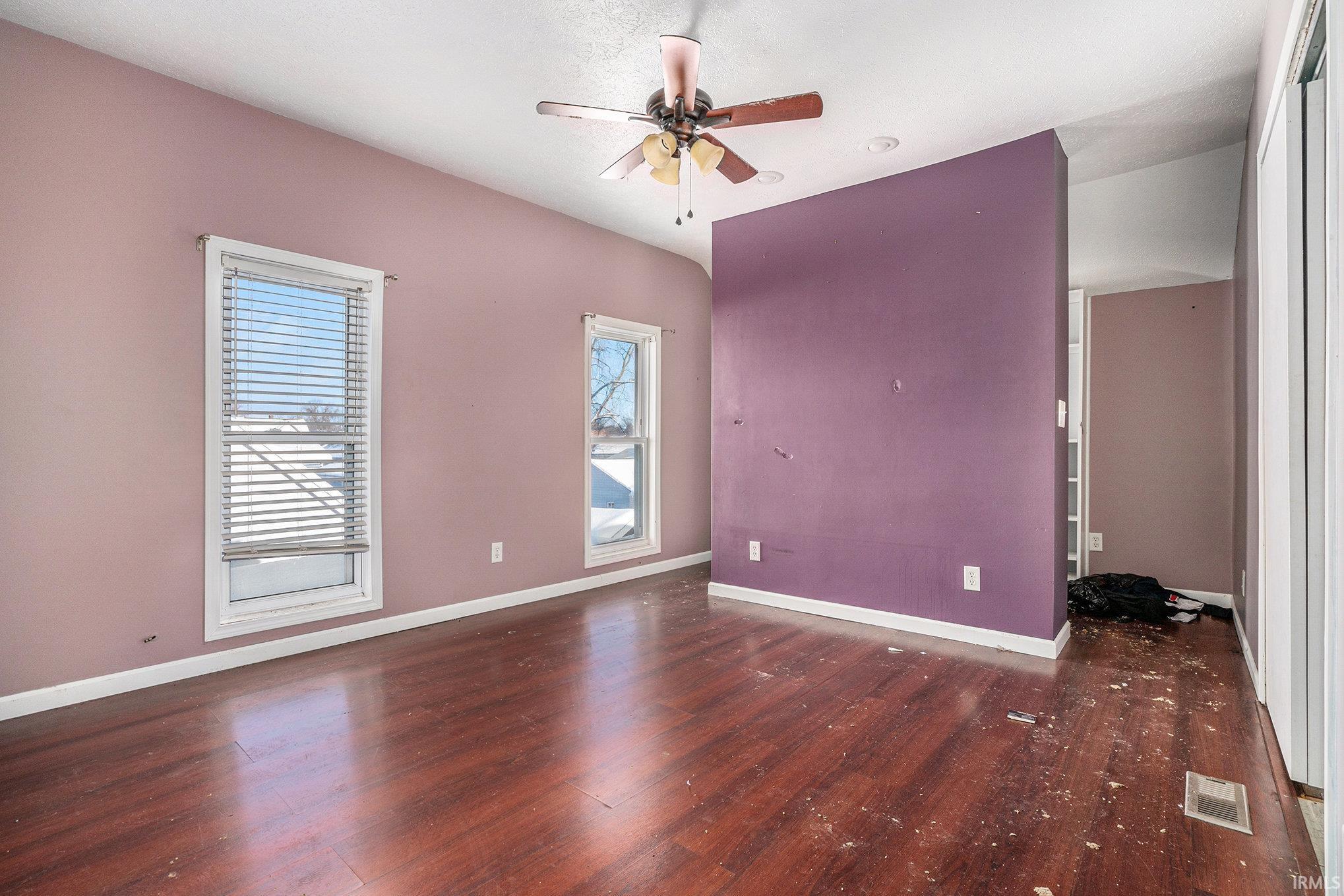 Empty room featuring dark wood-type flooring and ceiling fan