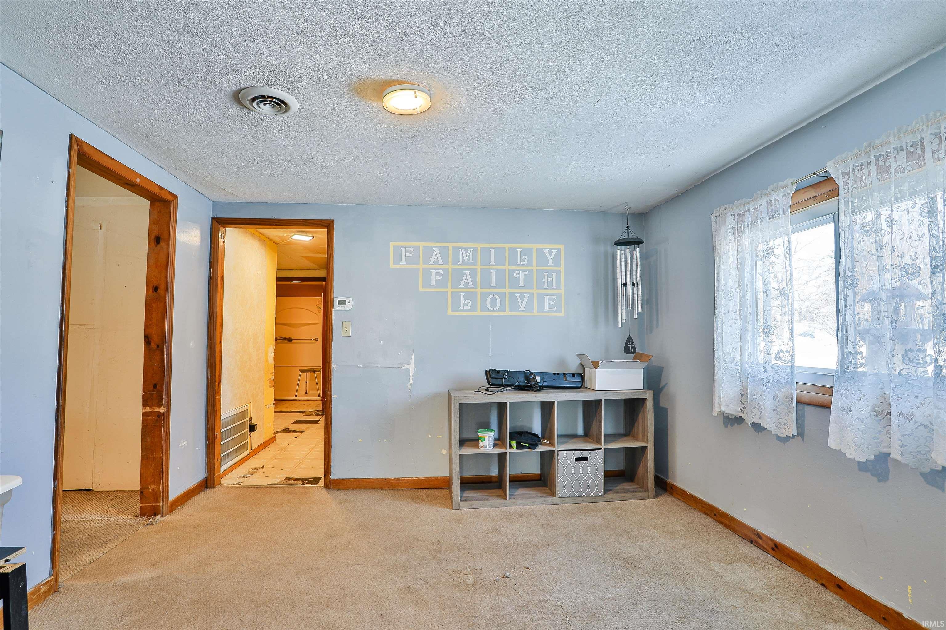 Carpeted bedroom featuring a textured ceiling and baseboards