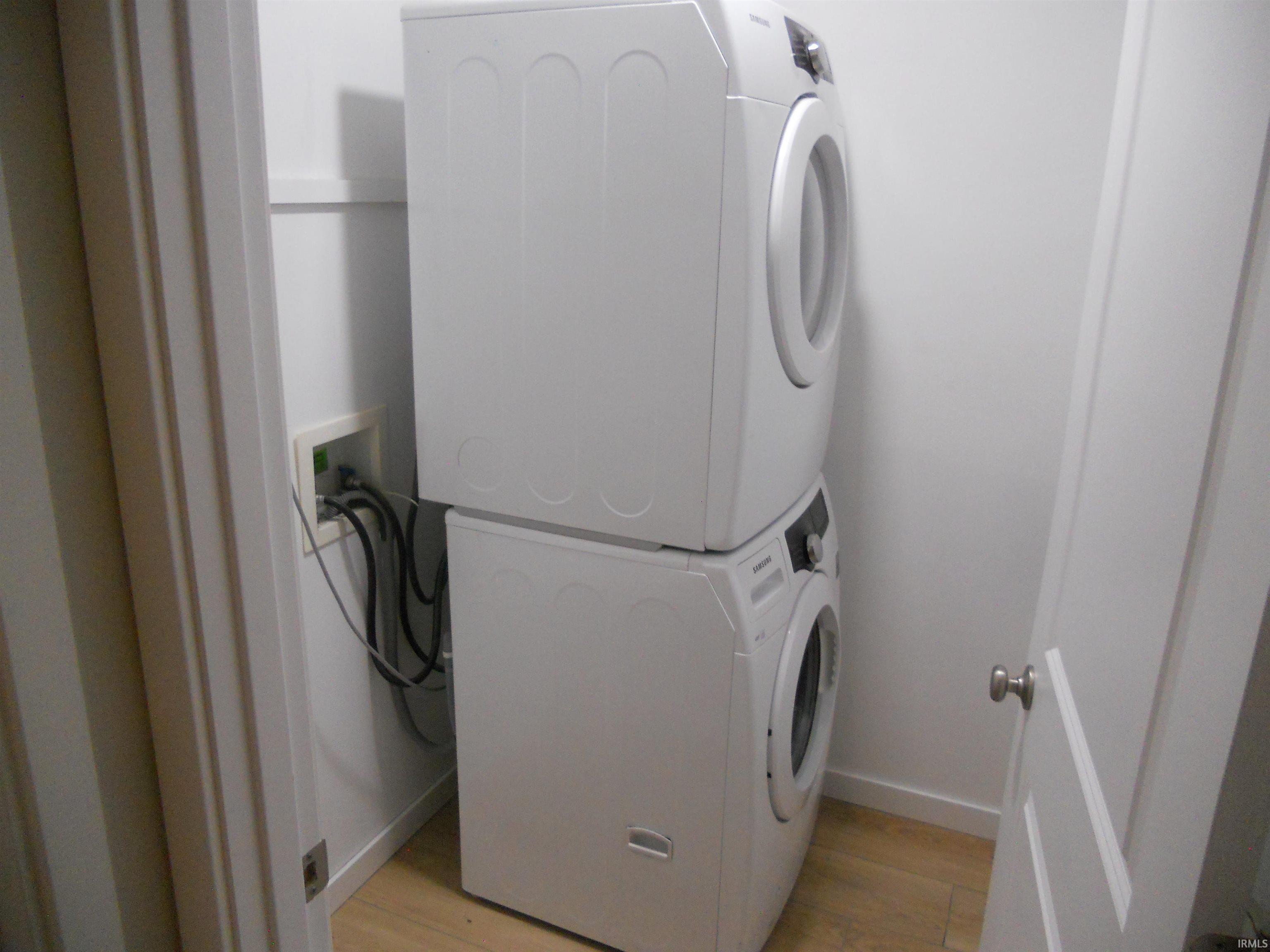 Laundry room featuring stacked washer / dryer and light wood finished floors