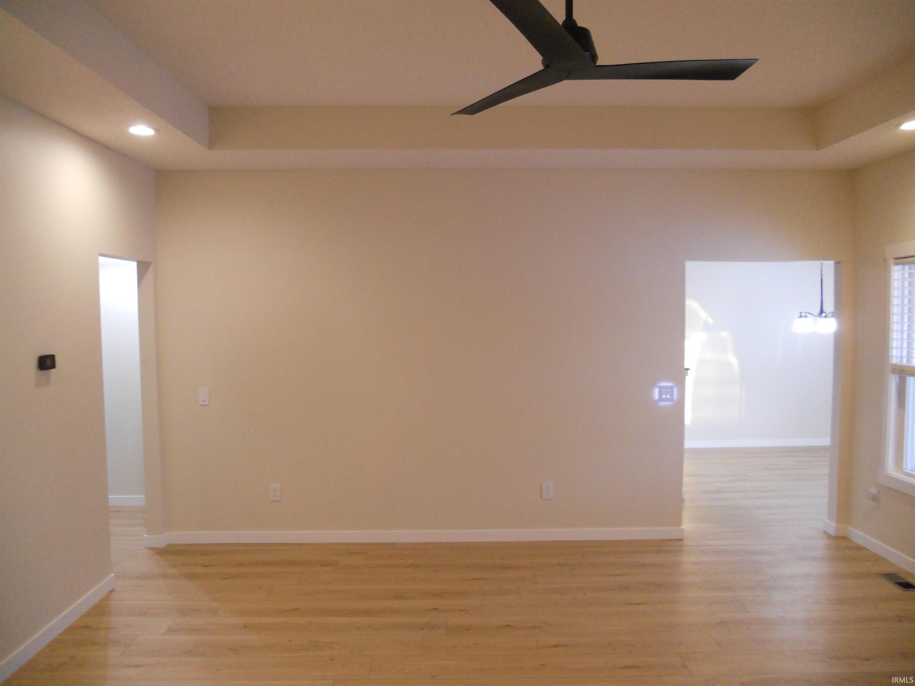 Unfurnished room with recessed lighting, light wood finished floors, a ceiling fan, and a tray ceiling