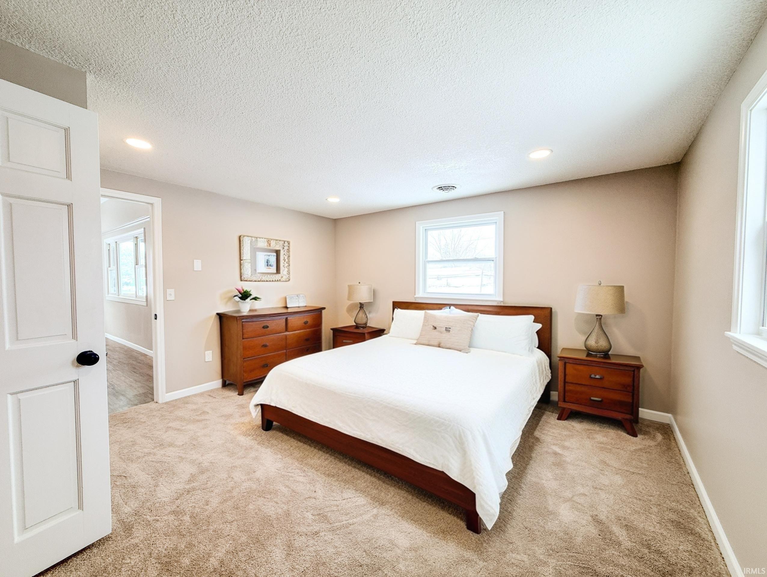 Bedroom with carpet flooring, multiple windows, a textured ceiling, and recessed lighting