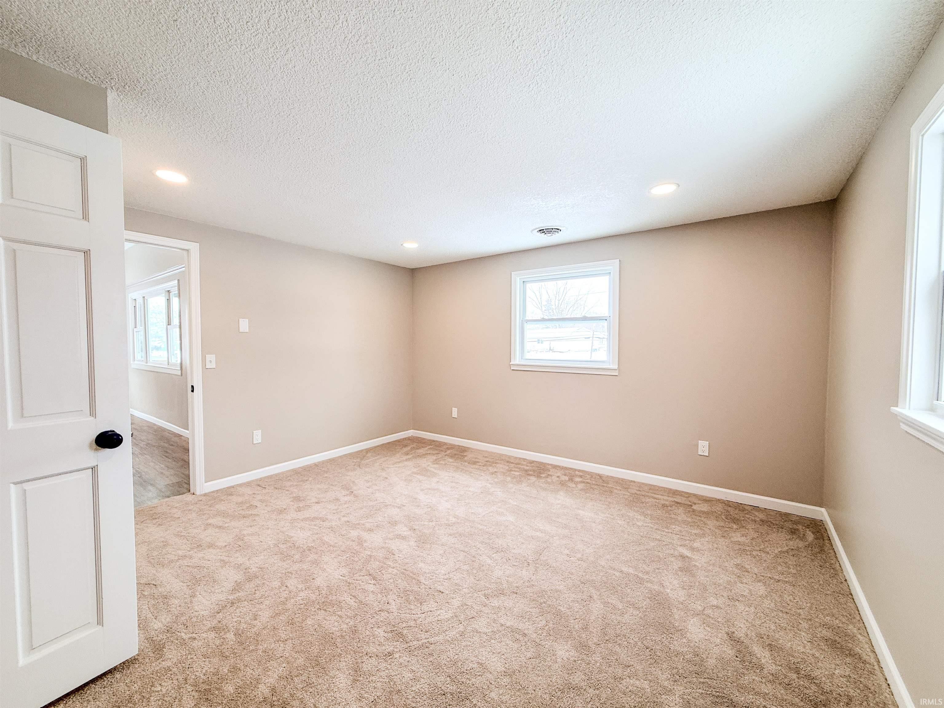 Unfurnished room with light carpet, healthy amount of natural light, recessed lighting, and a textured ceiling