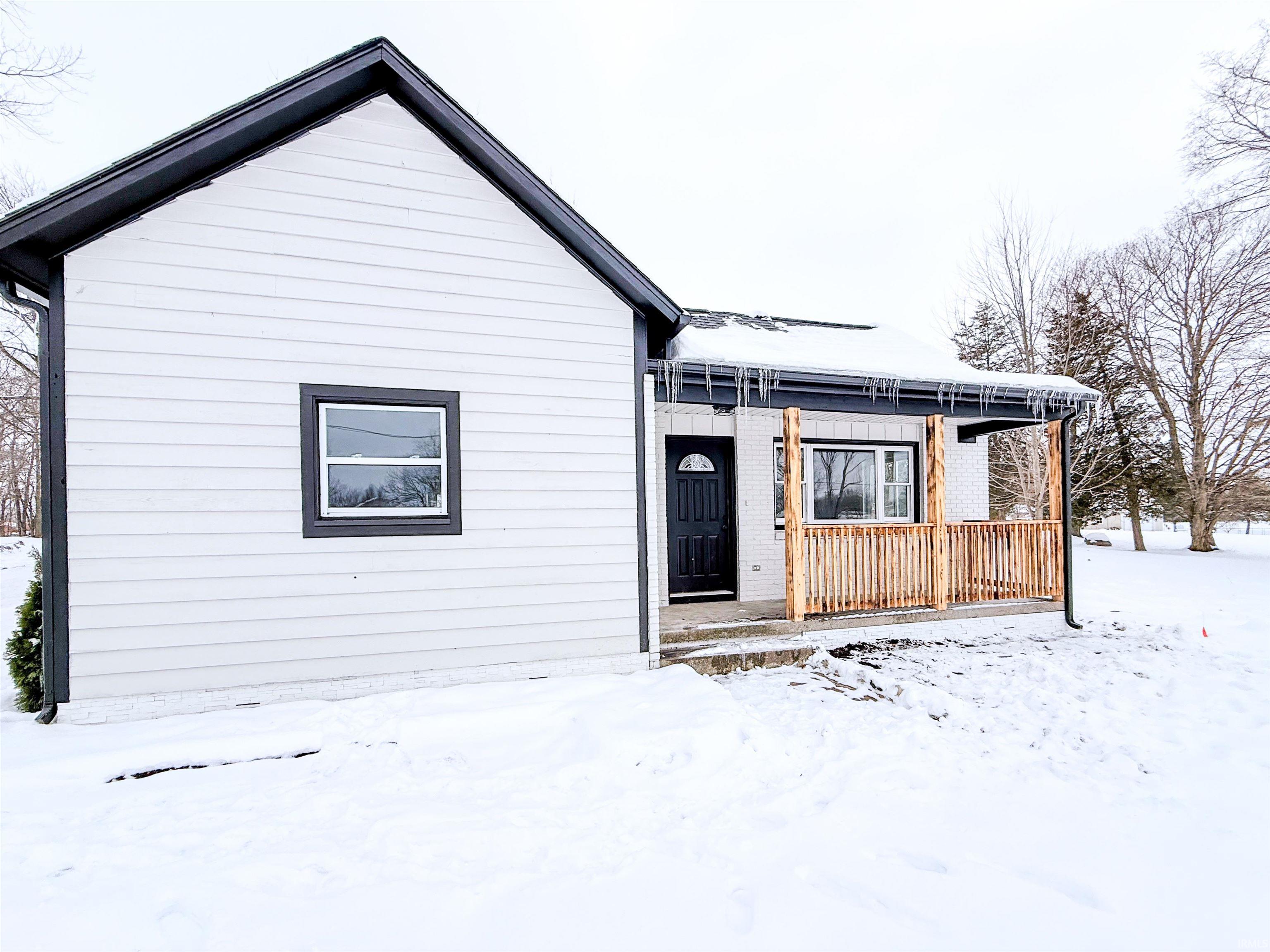 View of front of home featuring a wooden deck and brick siding