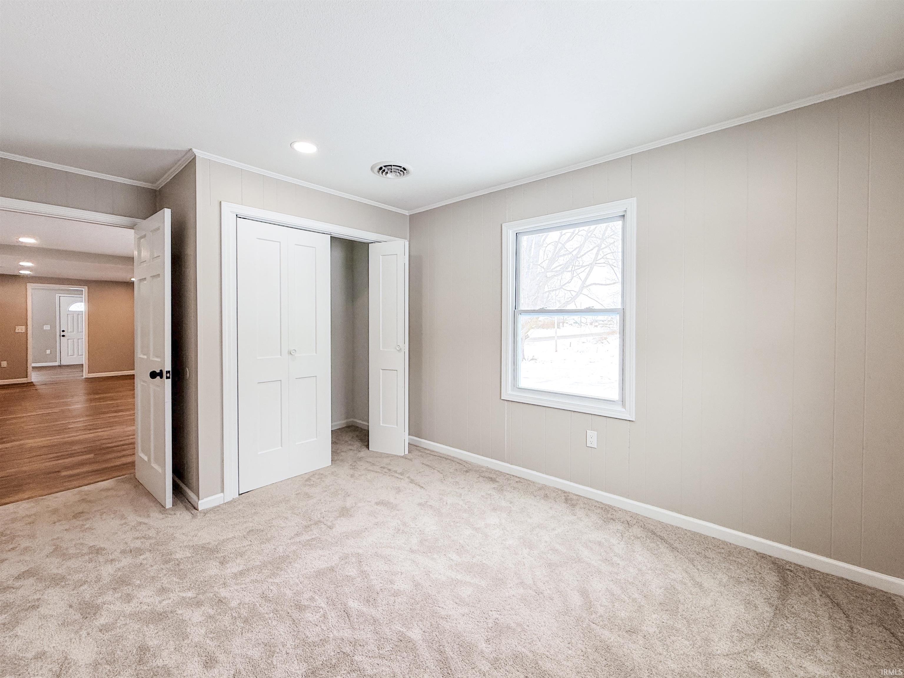Unfurnished bedroom featuring a closet, crown molding, light carpet, and recessed lighting