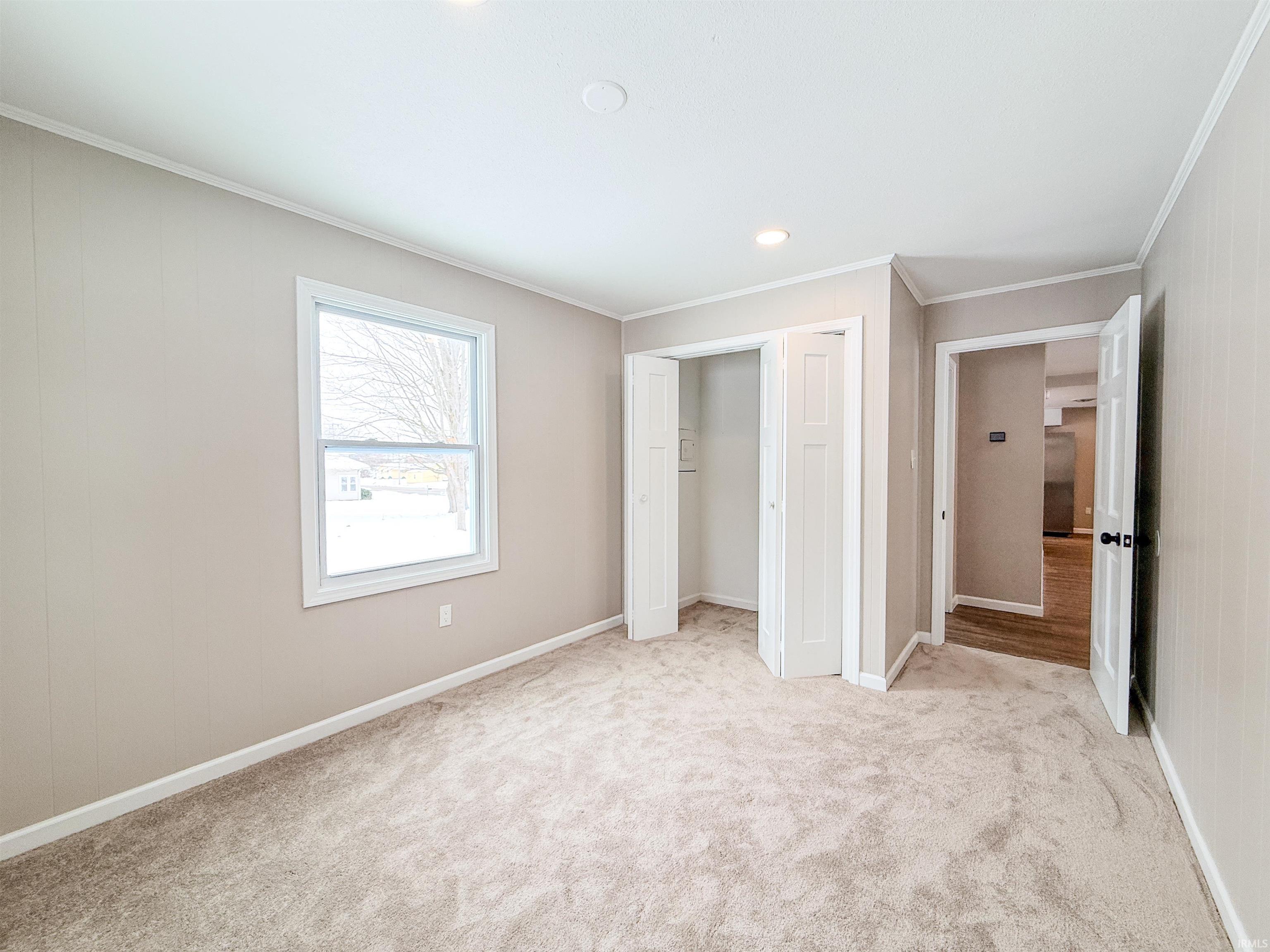 Unfurnished bedroom with ornamental molding, light colored carpet, a closet, and recessed lighting