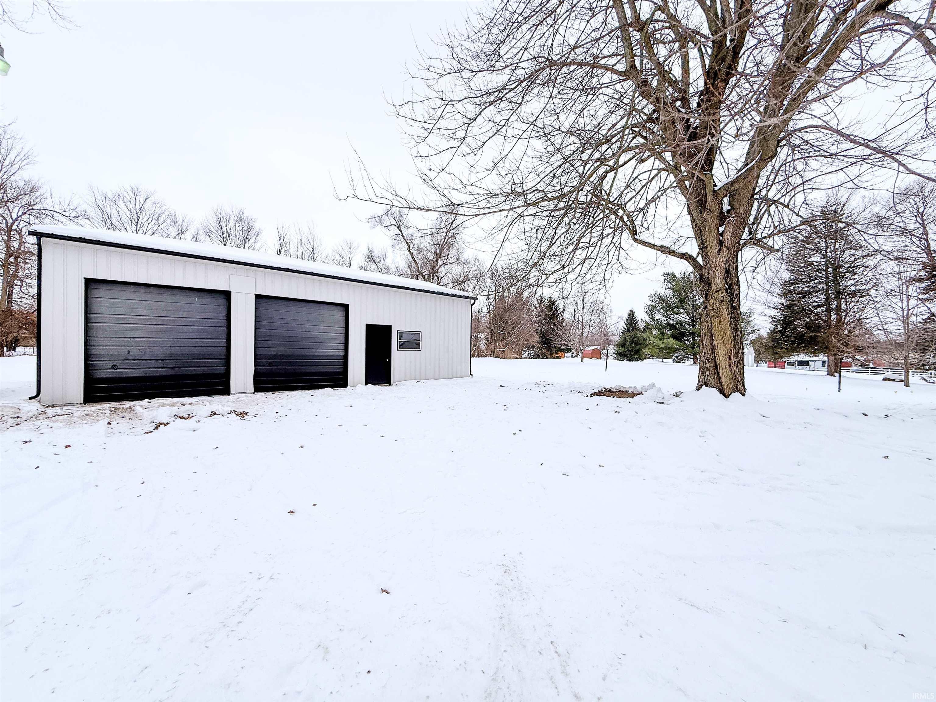 Snow covered garage with a detached garage