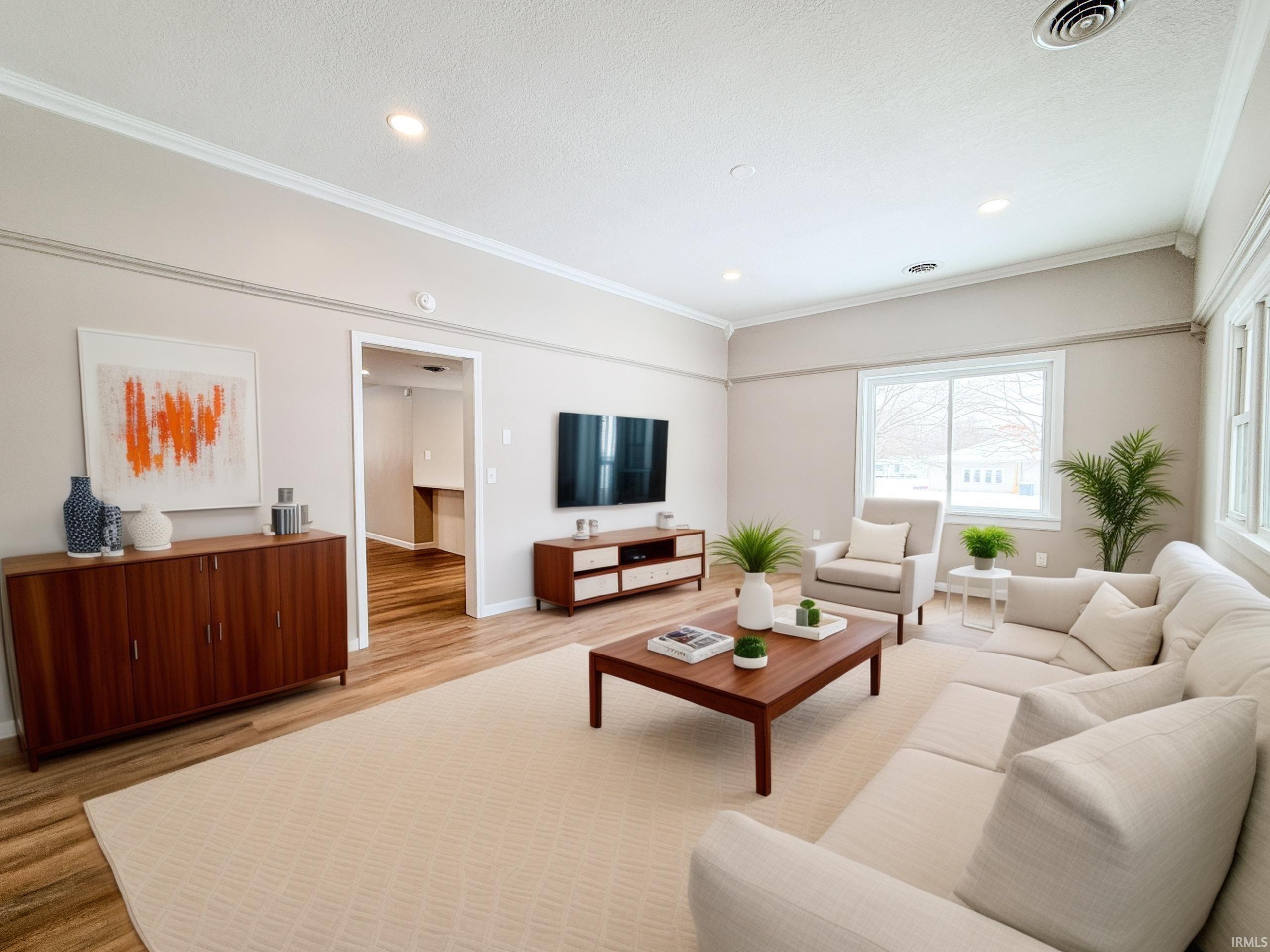 Living room featuring light wood-style floors, crown molding, and recessed lighting