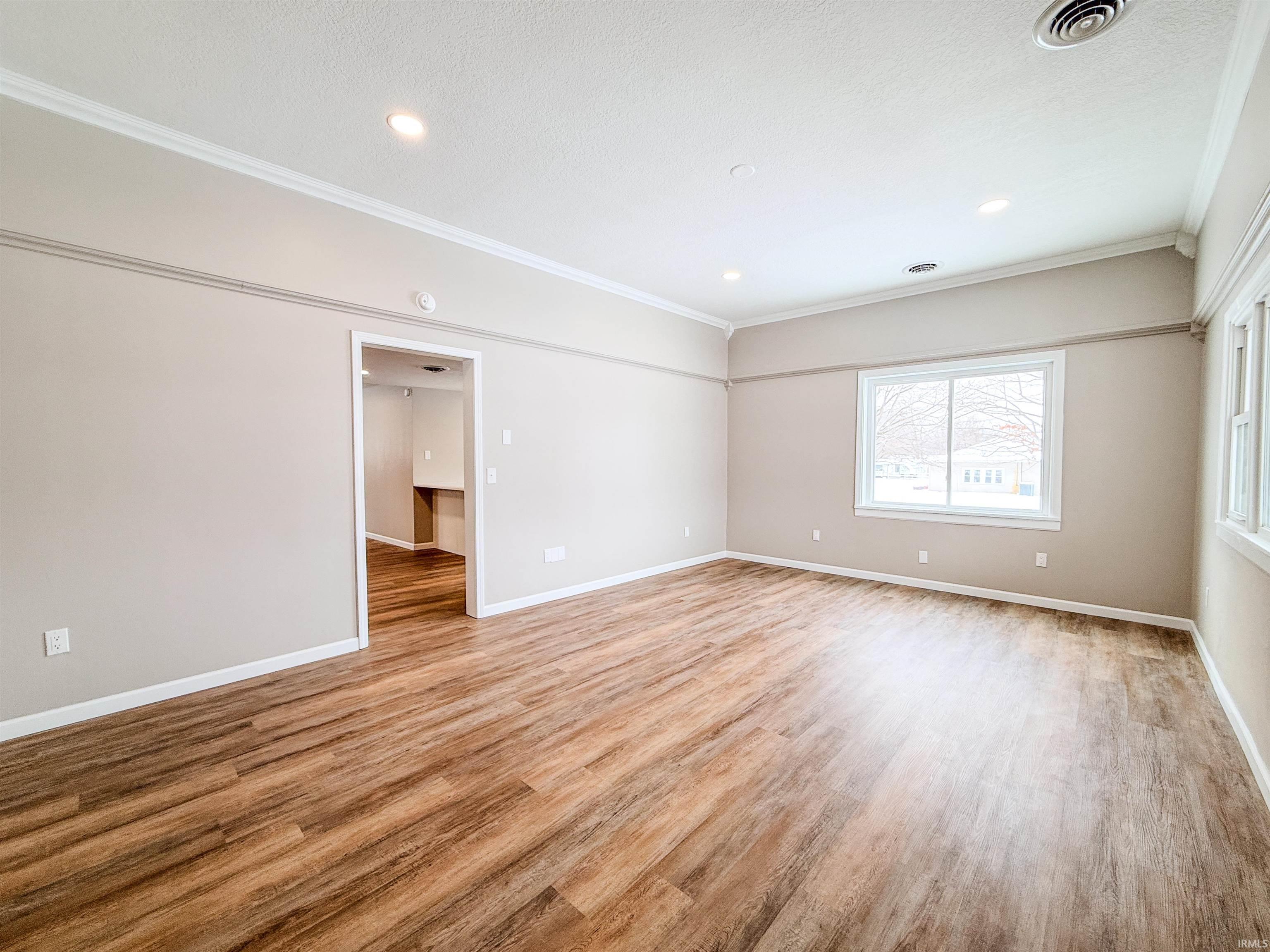 Empty room with ornamental molding, light wood finished floors, and recessed lighting