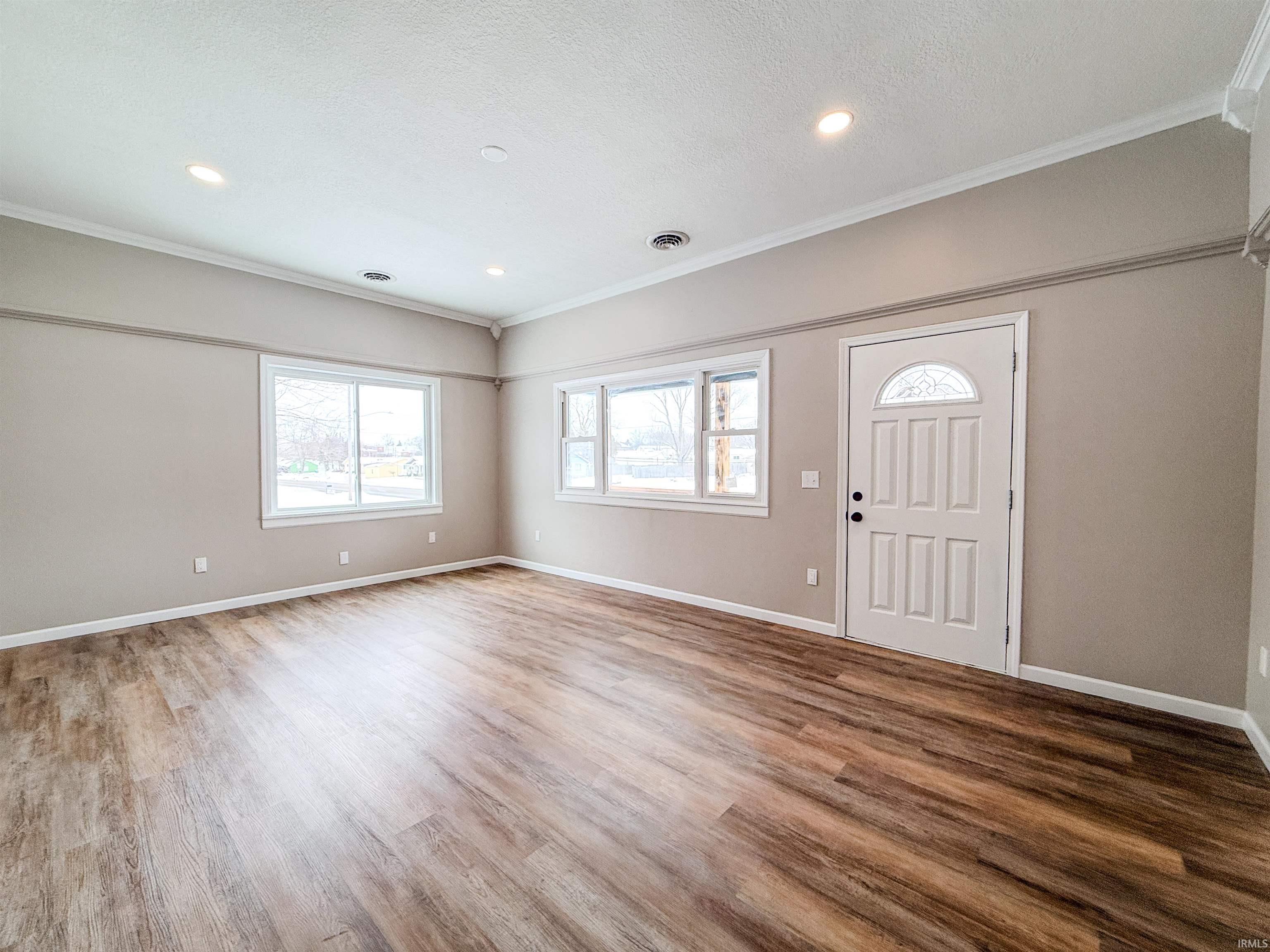 Entryway with ornamental molding, wood finished floors, recessed lighting, and a textured ceiling