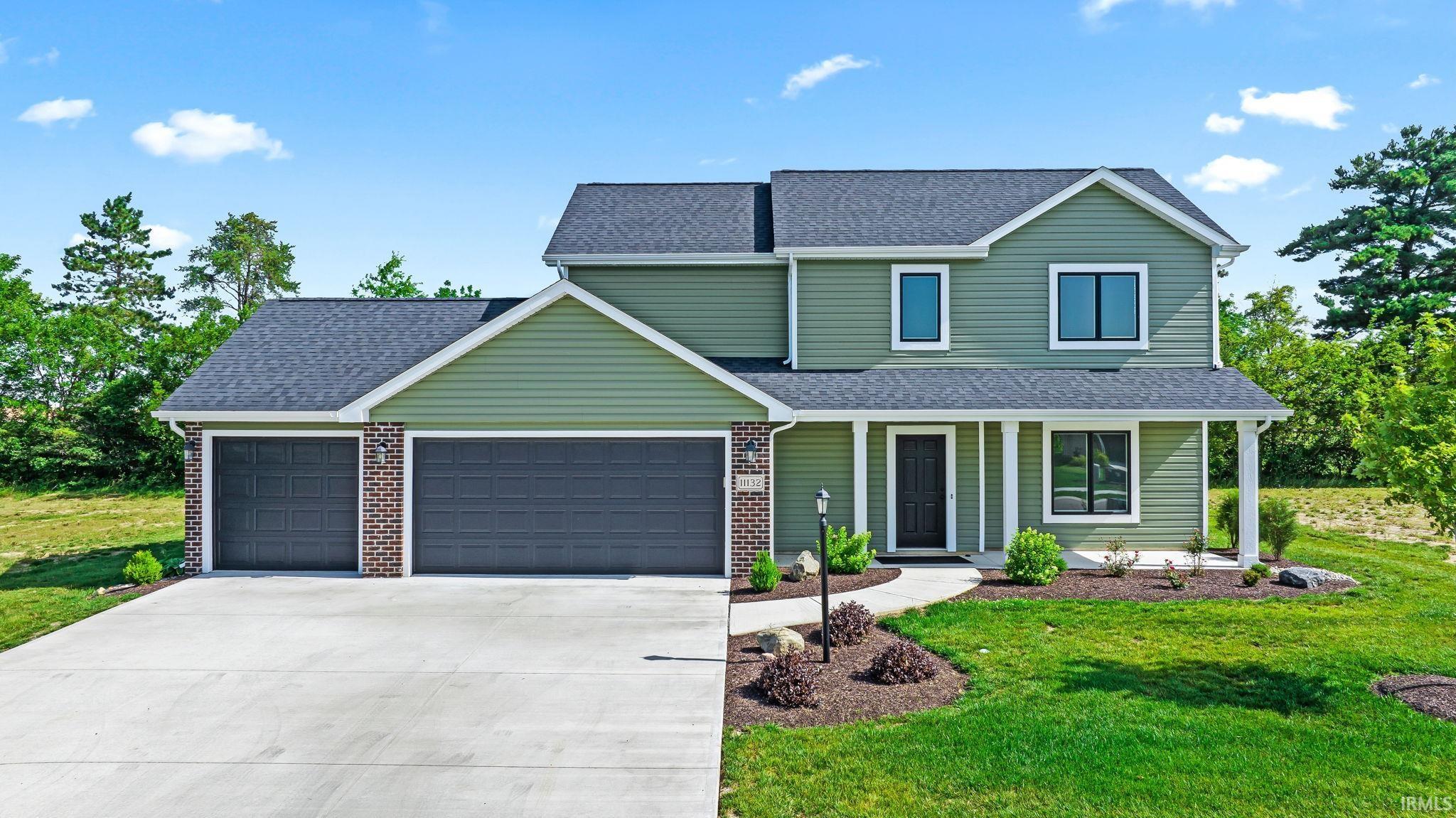 Two-story residence featuring green siding and dark shingle roofing