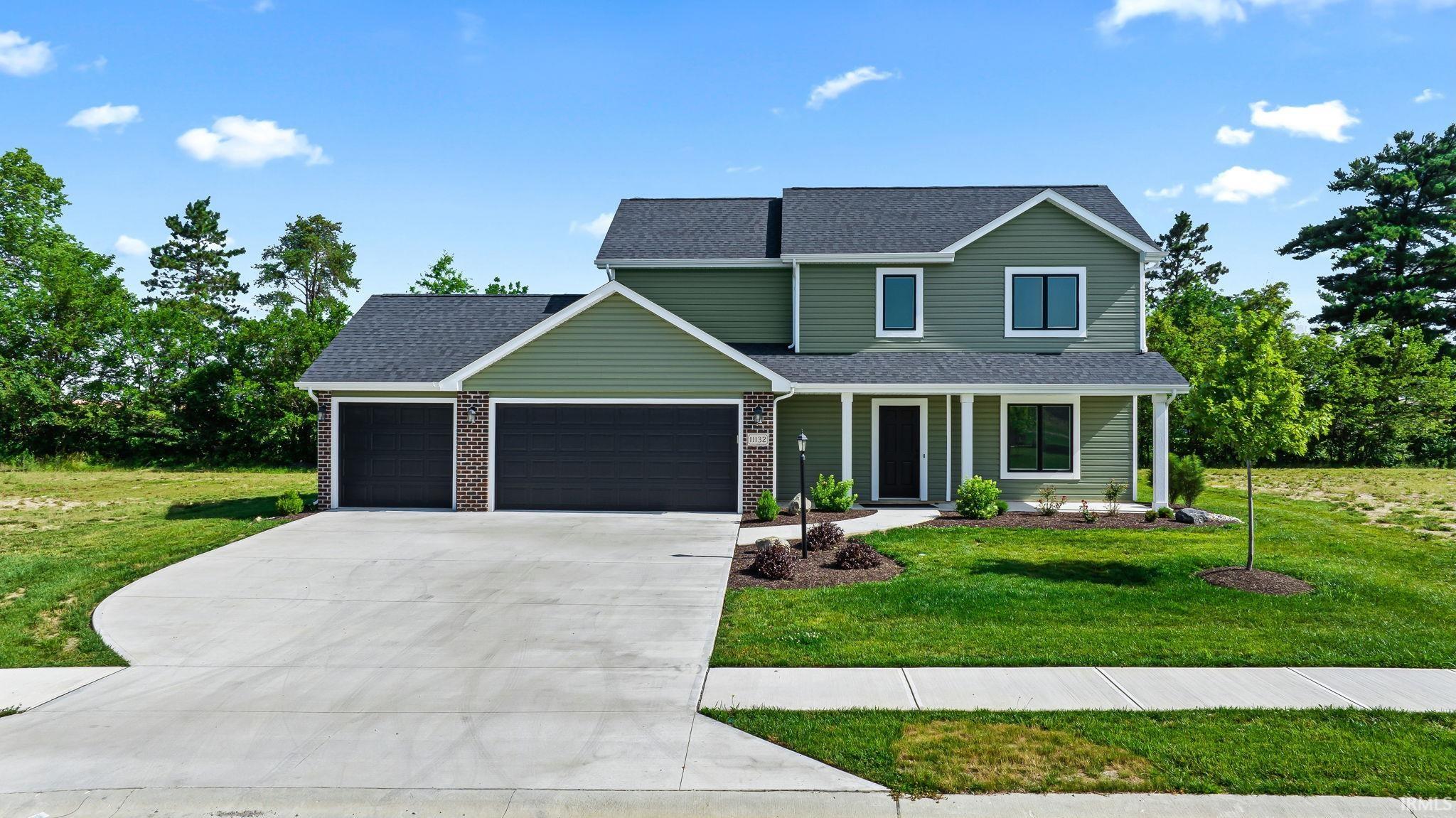 Contemporary two-story residence featuring green siding with white trim accents and a dark shingle roof
