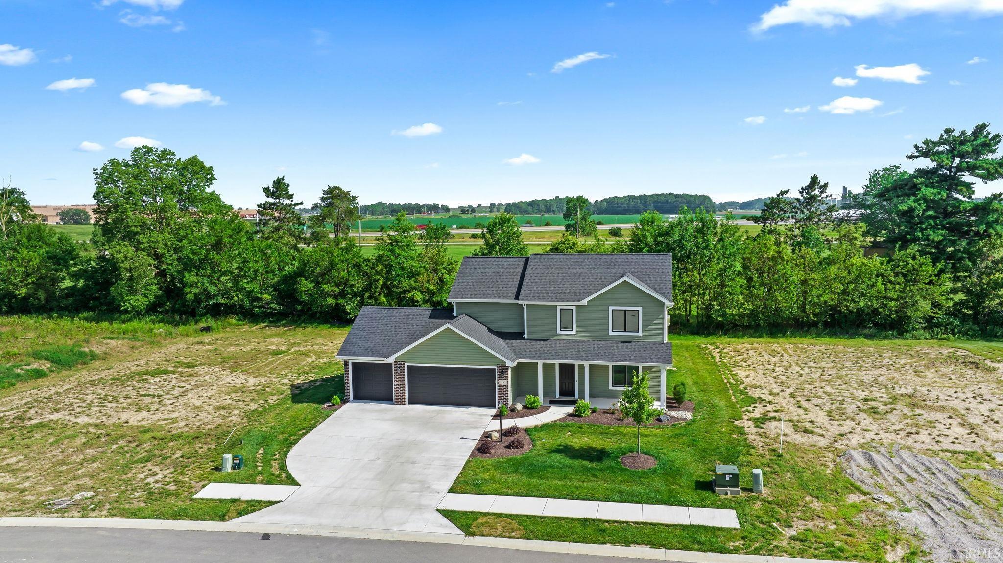 Contemporary two-story residence with a dark green exterior, featuring a symmetrical two-car garage with black doors