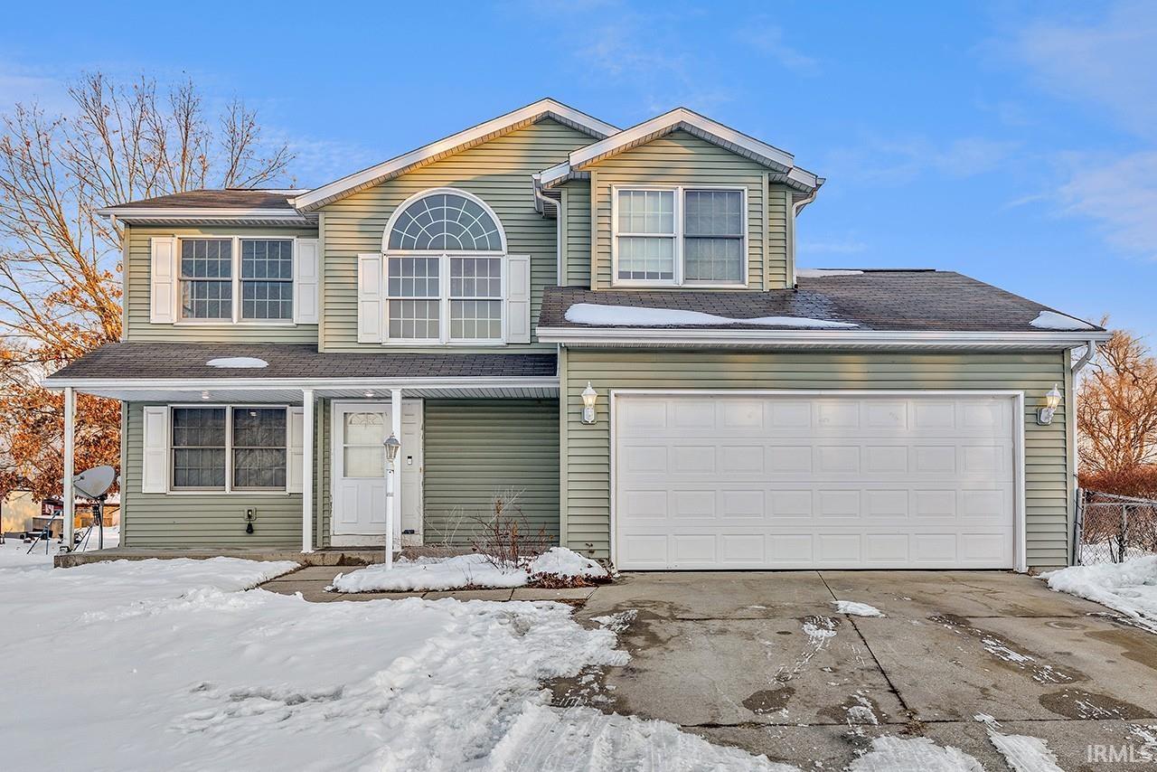 Traditional home featuring a shingled roof and concrete driveway