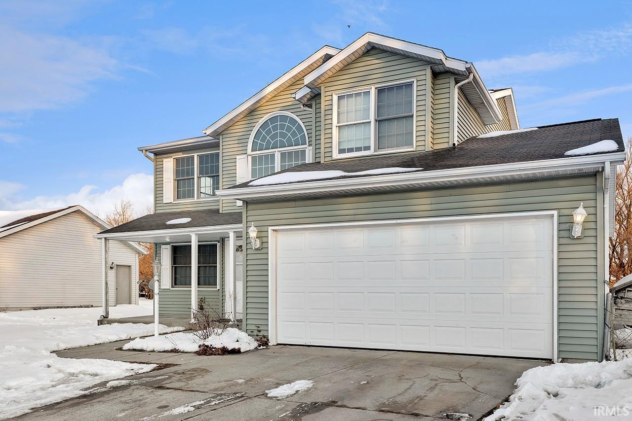 Traditional home featuring a porch, driveway, a garage, and roof with shingles