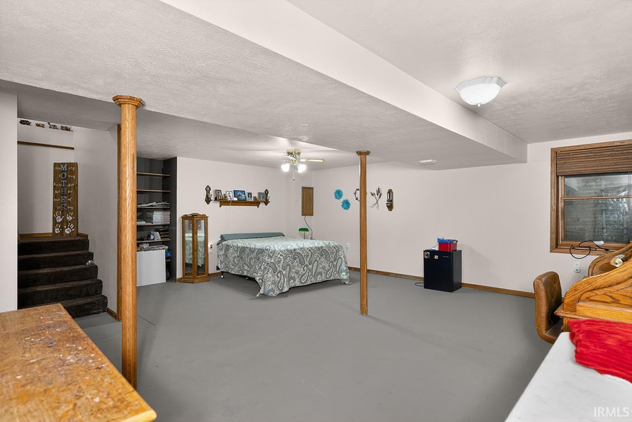 Bedroom featuring concrete floors, a textured ceiling, ceiling fan, and black refrigerator