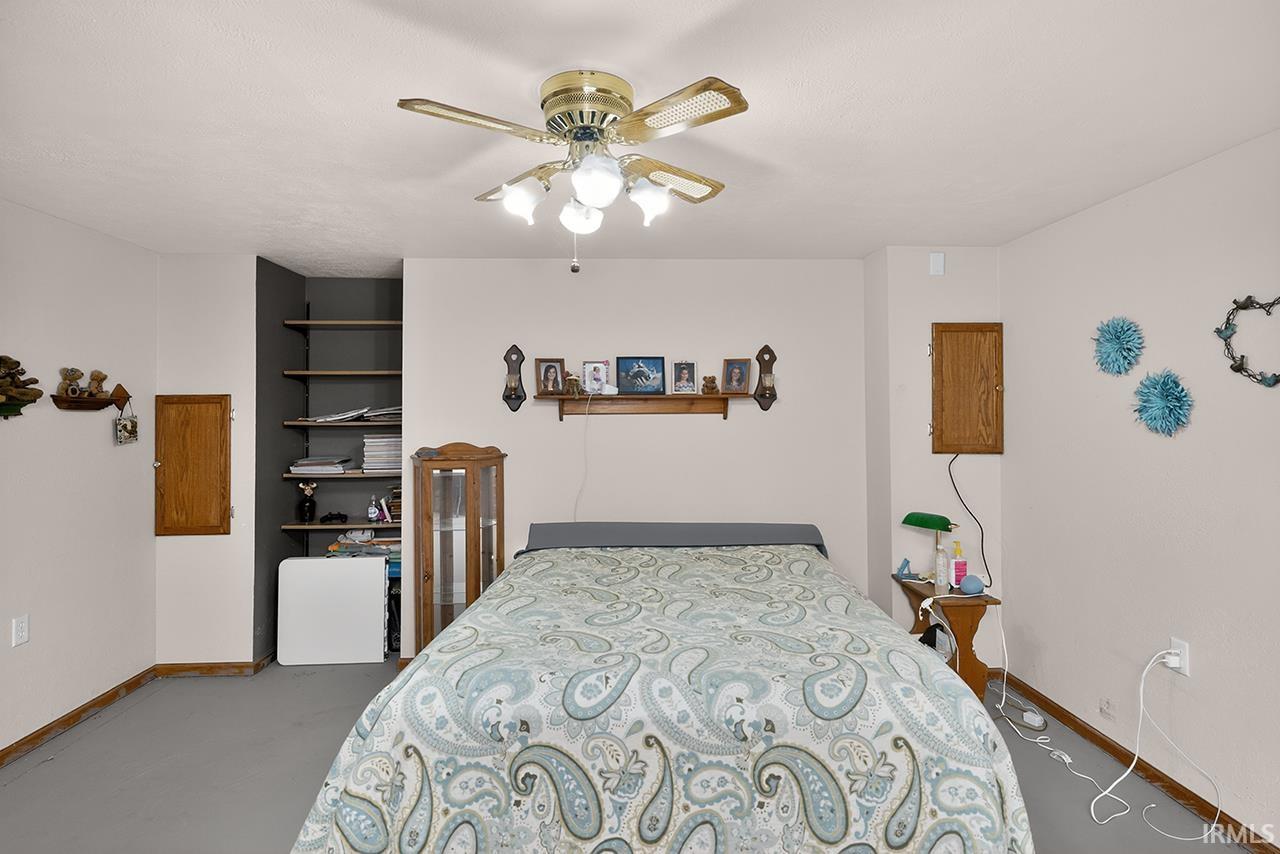 Bedroom with ceiling fan and concrete floors