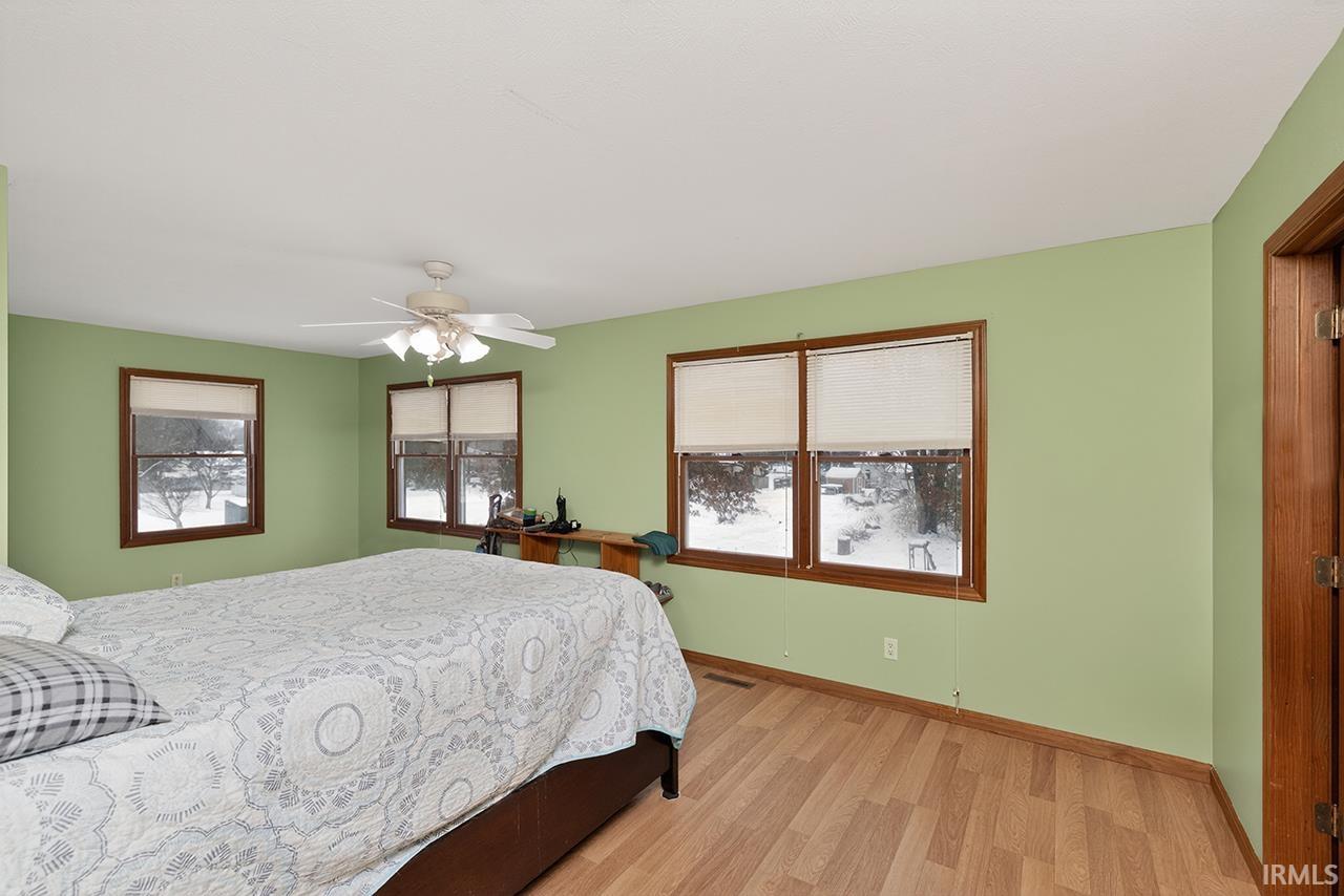 Bedroom featuring a ceiling fan, light wood-type flooring, and multiple windows