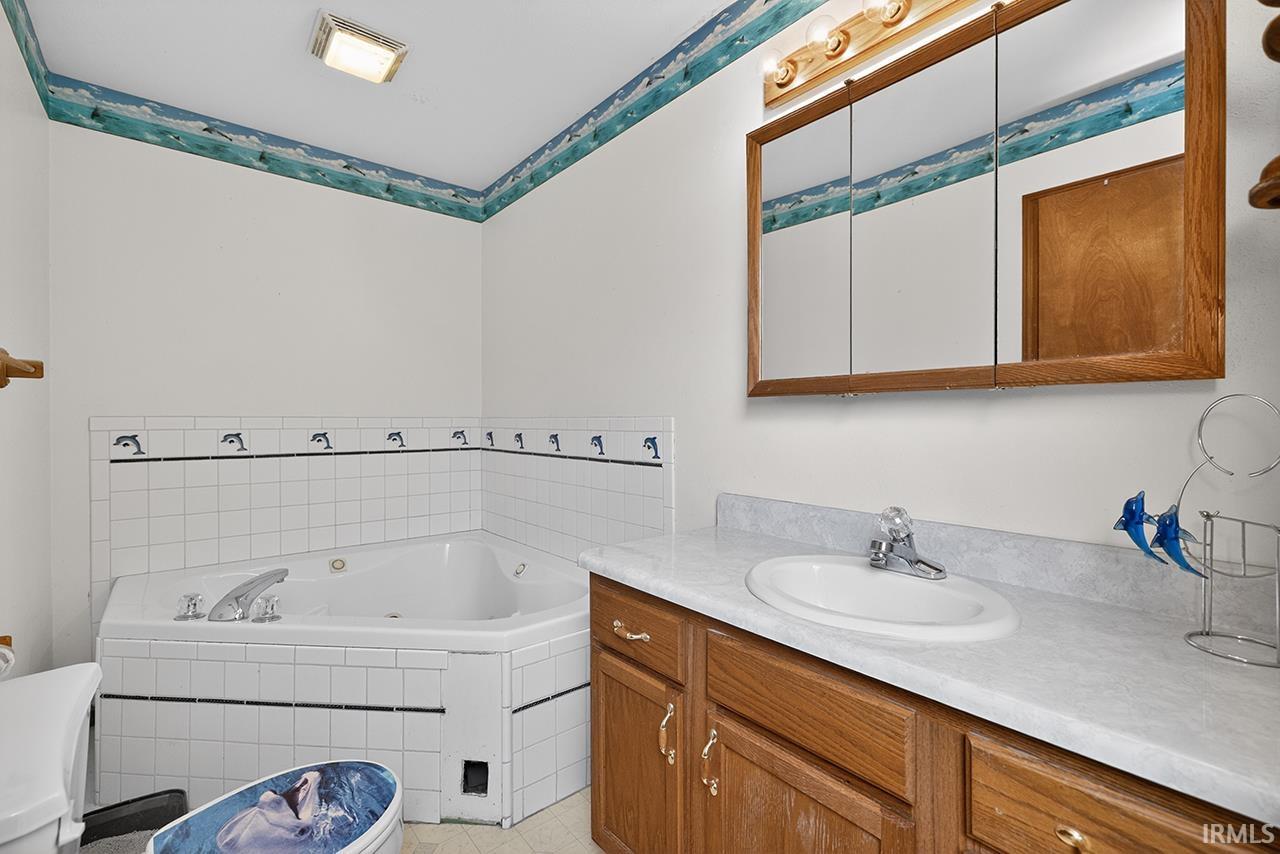 Full bathroom featuring vanity and a tub with jets