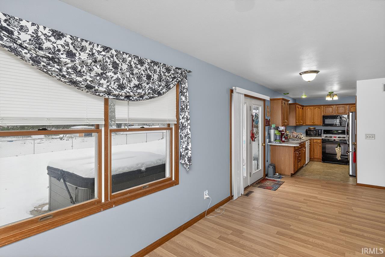 Kitchen with light countertops, brown cabinets, black appliances, and light wood-type flooring