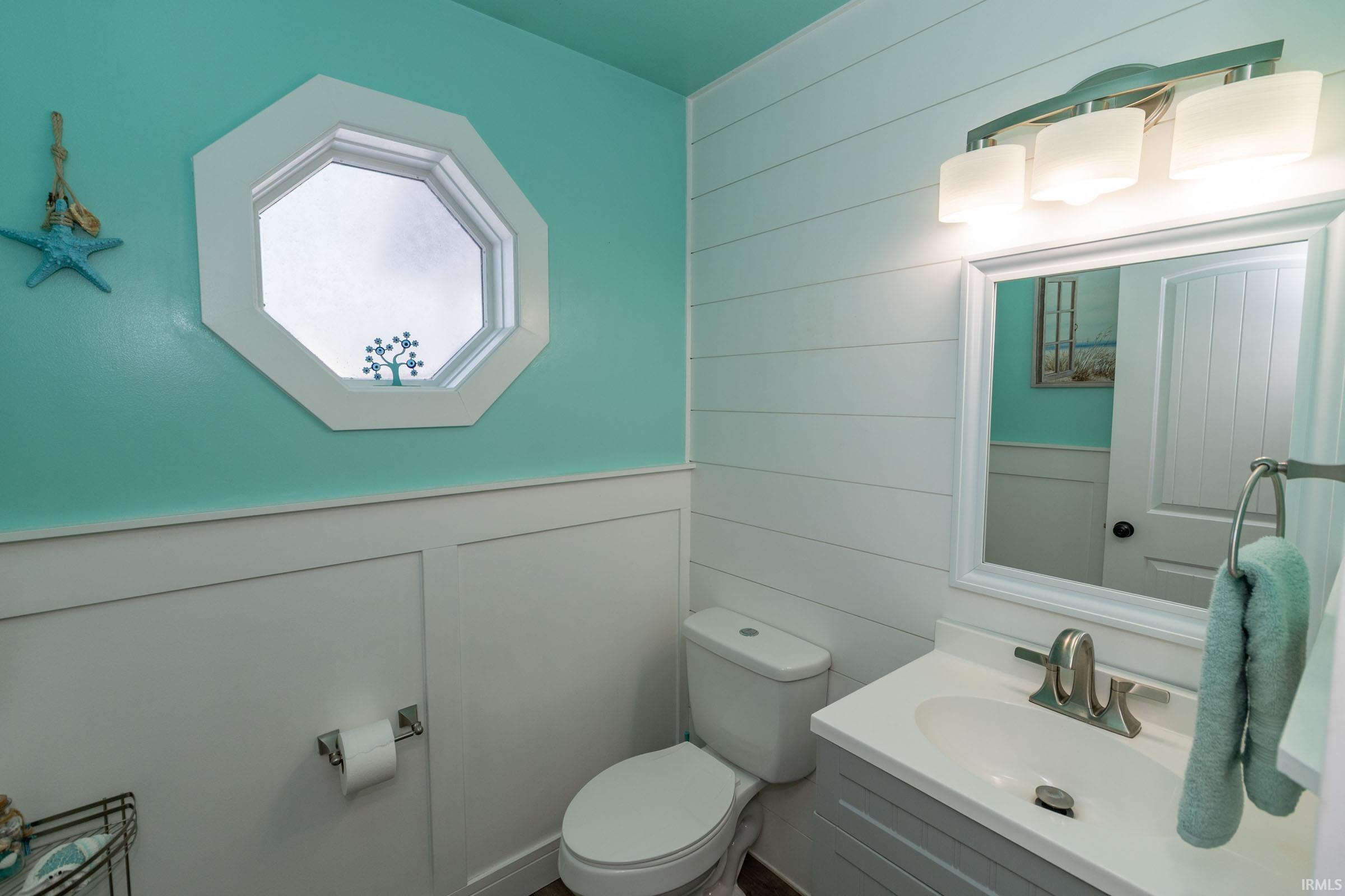 Bathroom with vanity, wooden walls, a decorative wall, and wainscoting