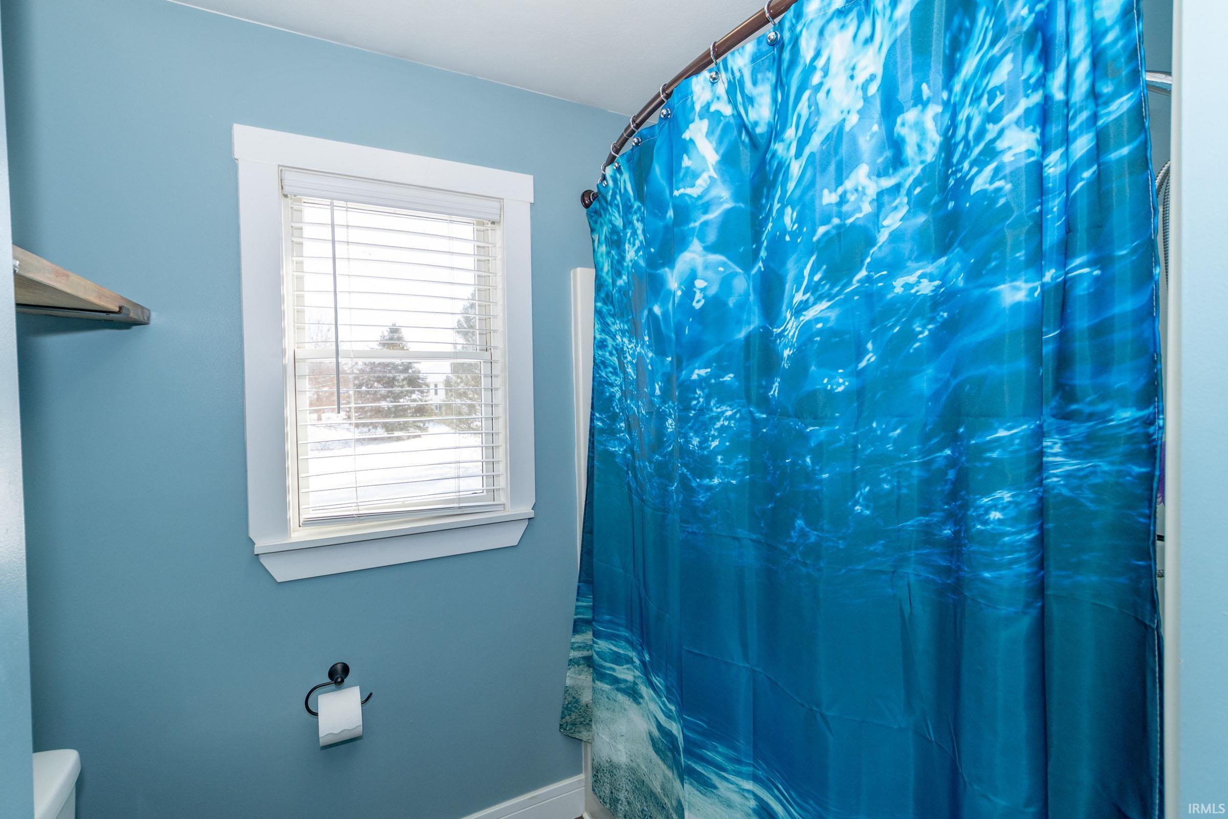 Bathroom featuring a shower with shower curtain and toilet