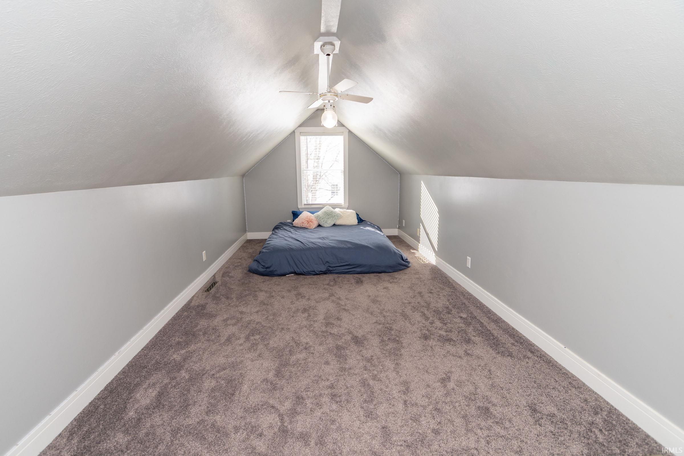 Carpeted bedroom featuring lofted ceiling, a ceiling fan, and a textured ceiling