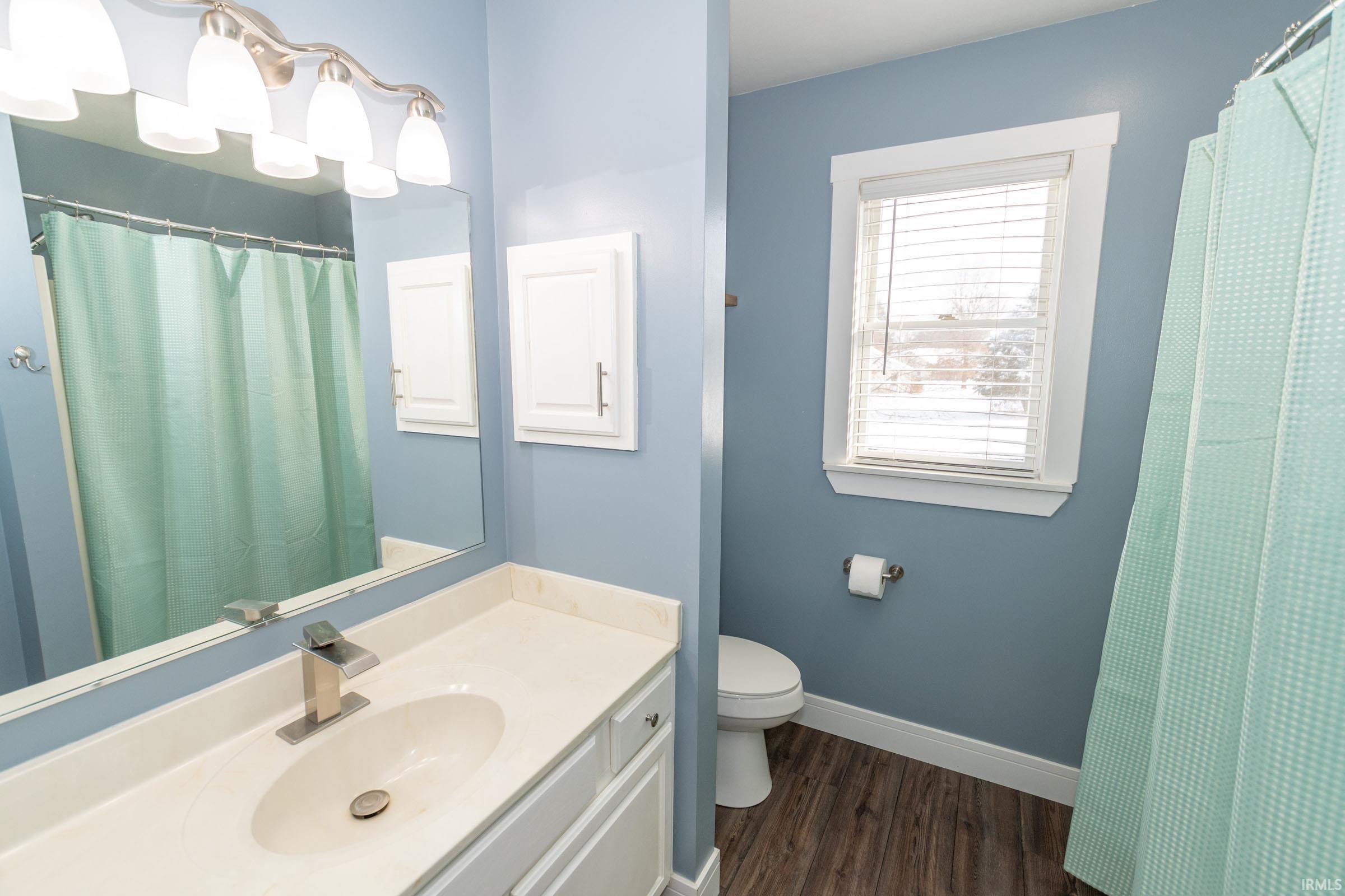 Bathroom featuring a shower with curtain, vanity, and dark wood-style floors