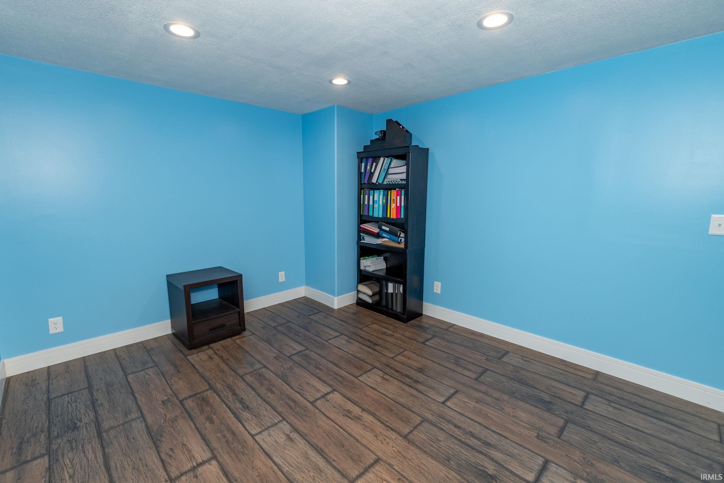 Unfurnished room featuring dark wood-type flooring, a textured ceiling, and recessed lighting