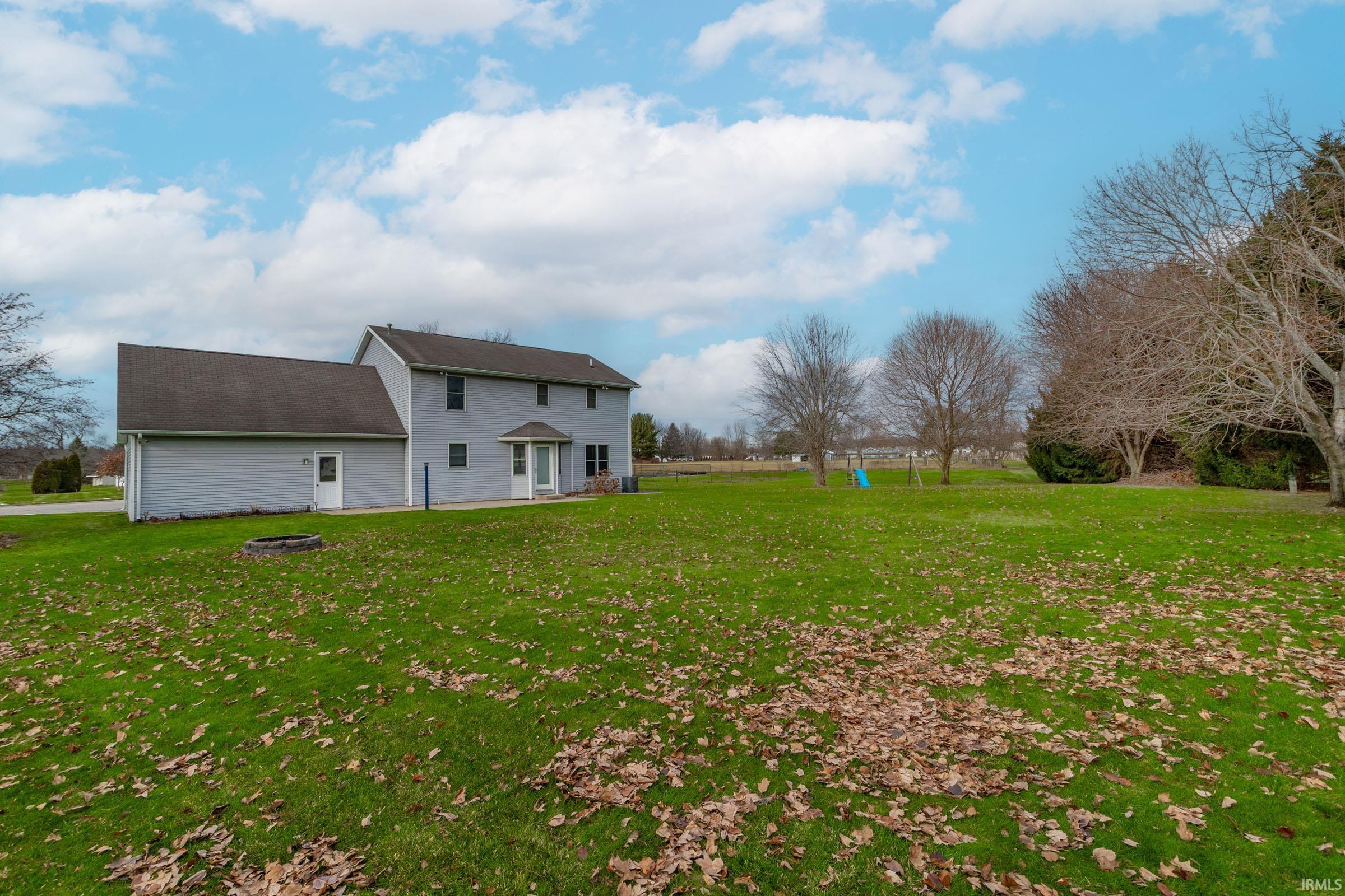 Rear view of property with a lawn and a fire pit