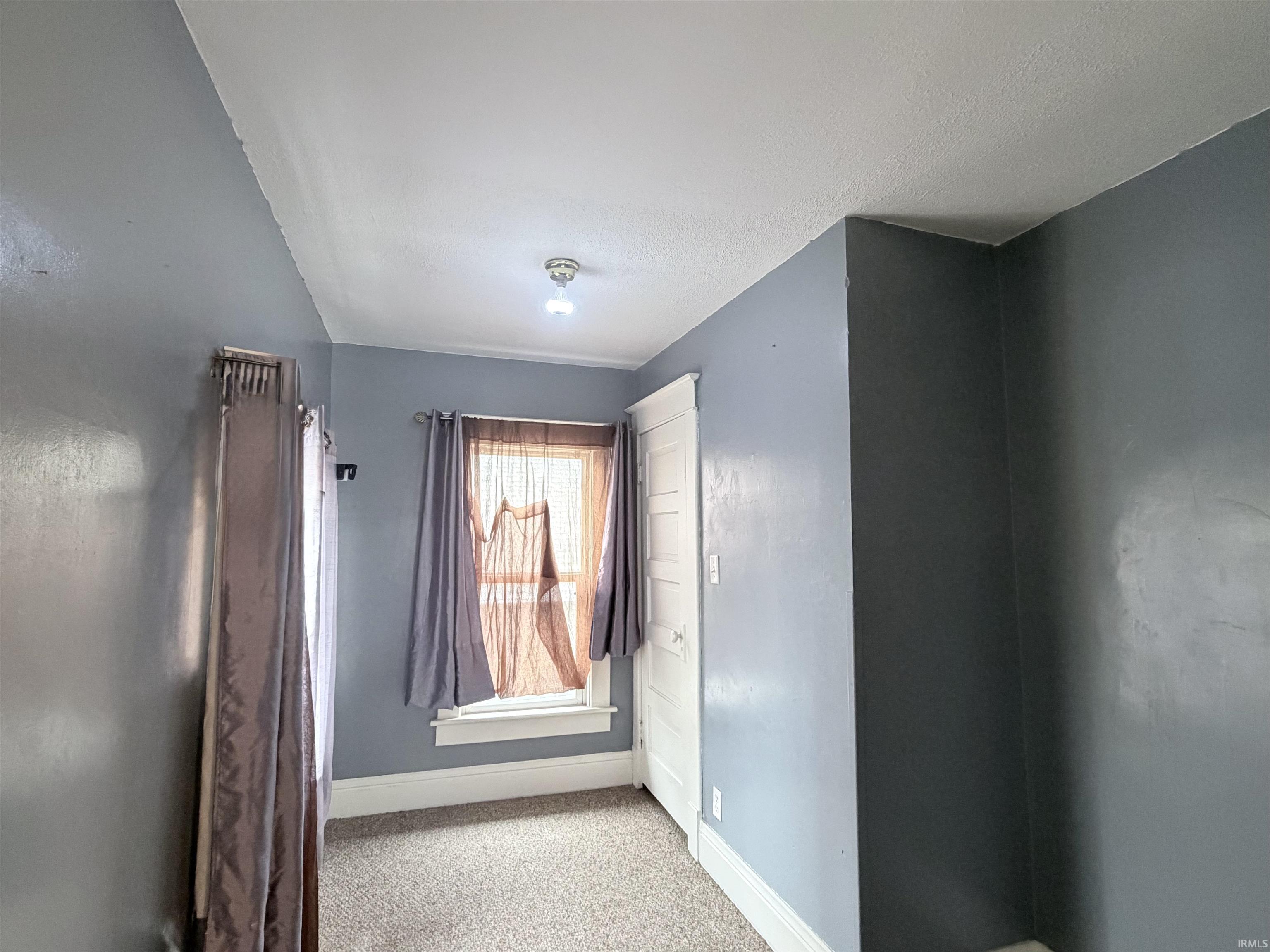 Empty room with baseboards and light colored carpet