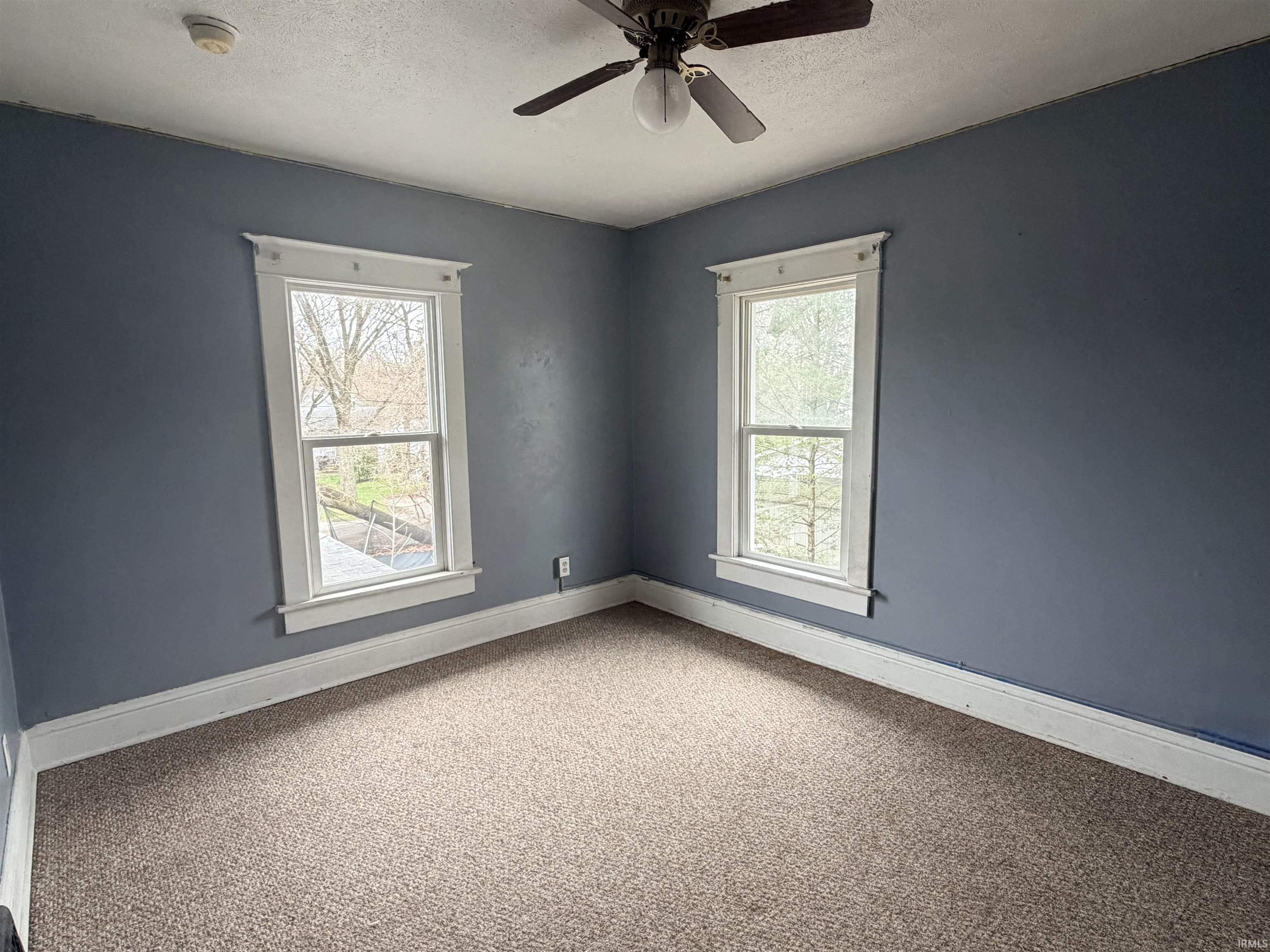 Spare room featuring carpet, a textured ceiling, a ceiling fan, and a smoke detector