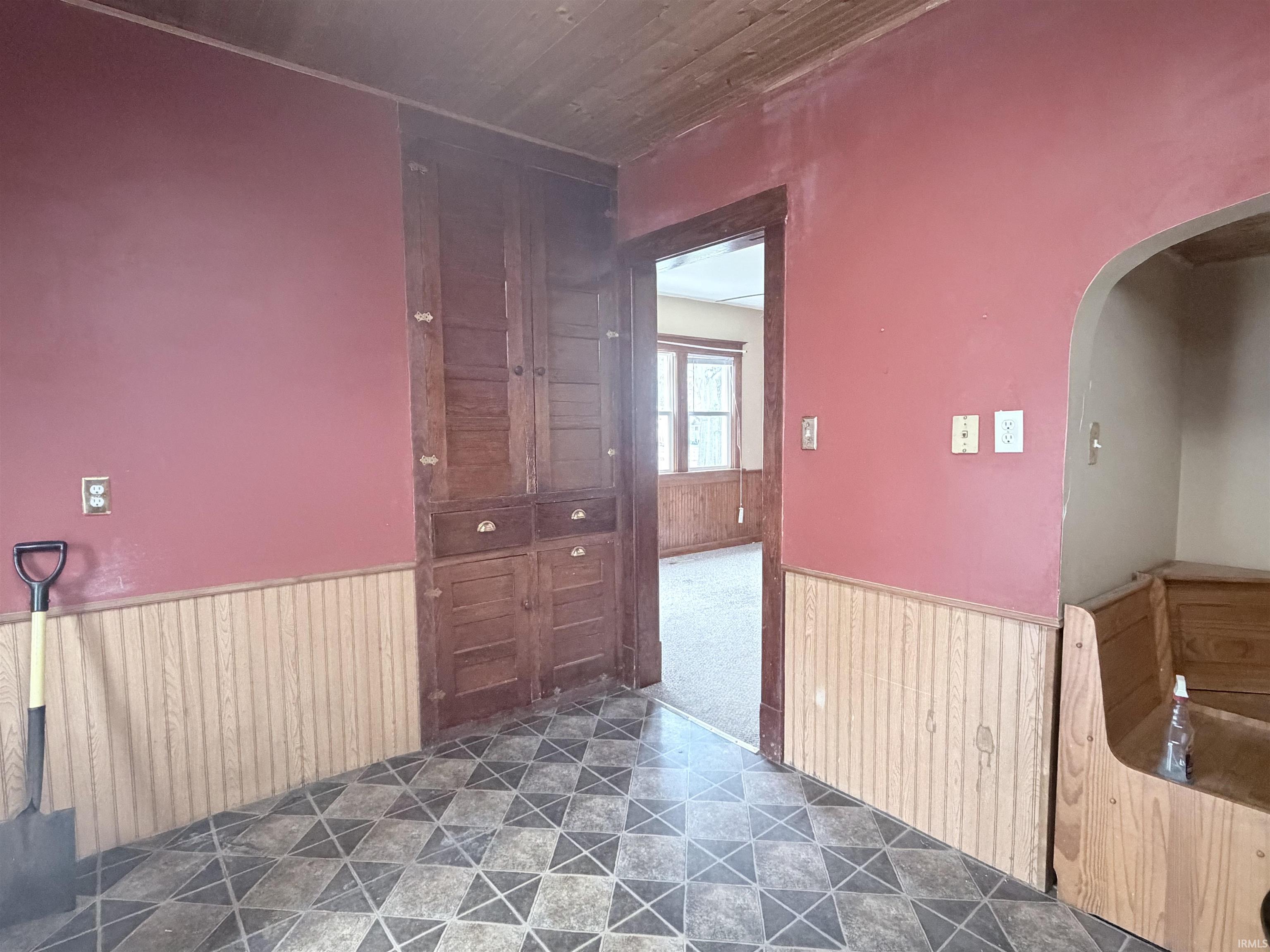 Spare room with wood walls, wainscoting, arched walkways, and wooden ceiling